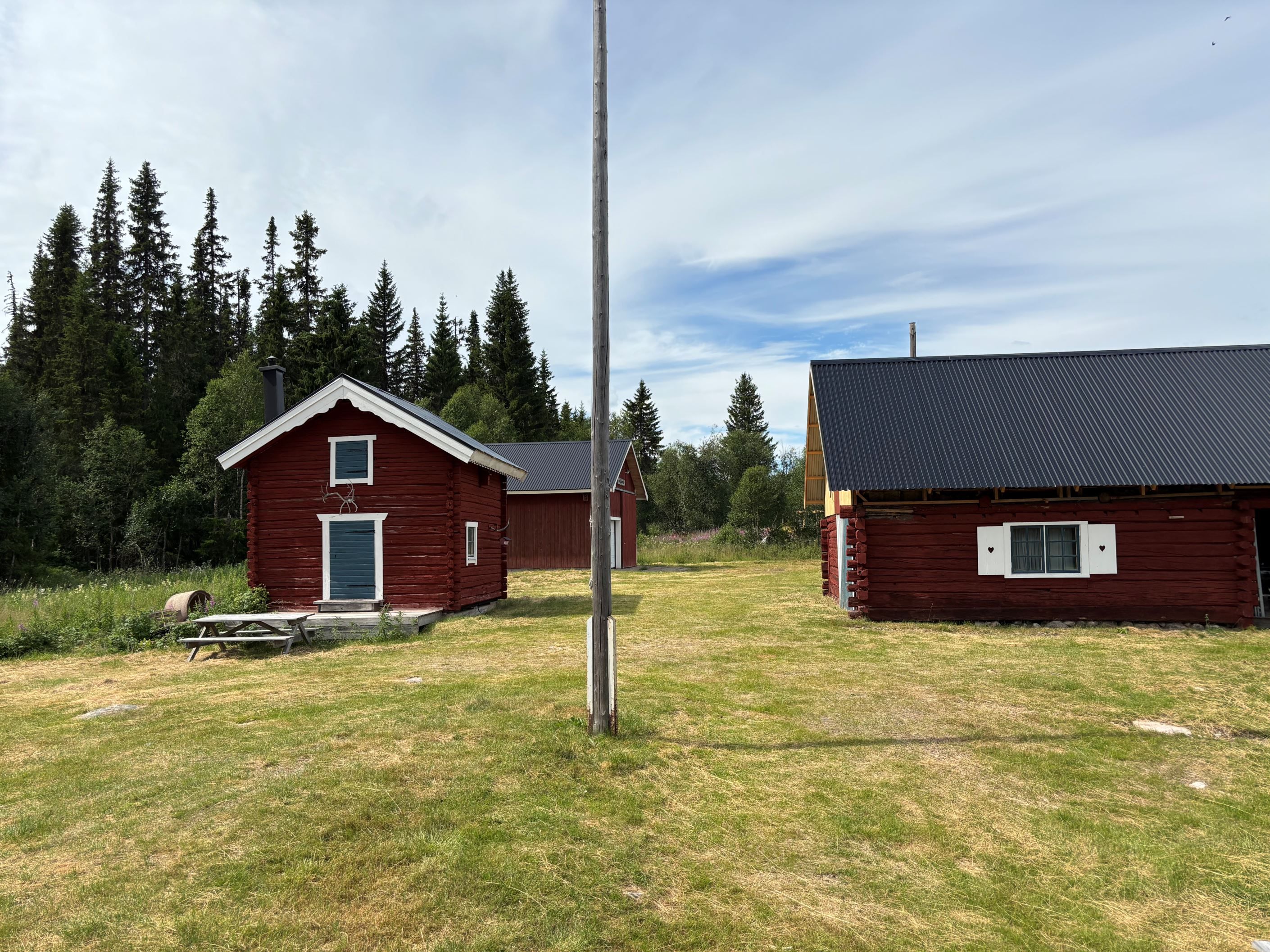 Gården sett från huset med härbre och garage t.v i bild och stora ladan t.h i bild