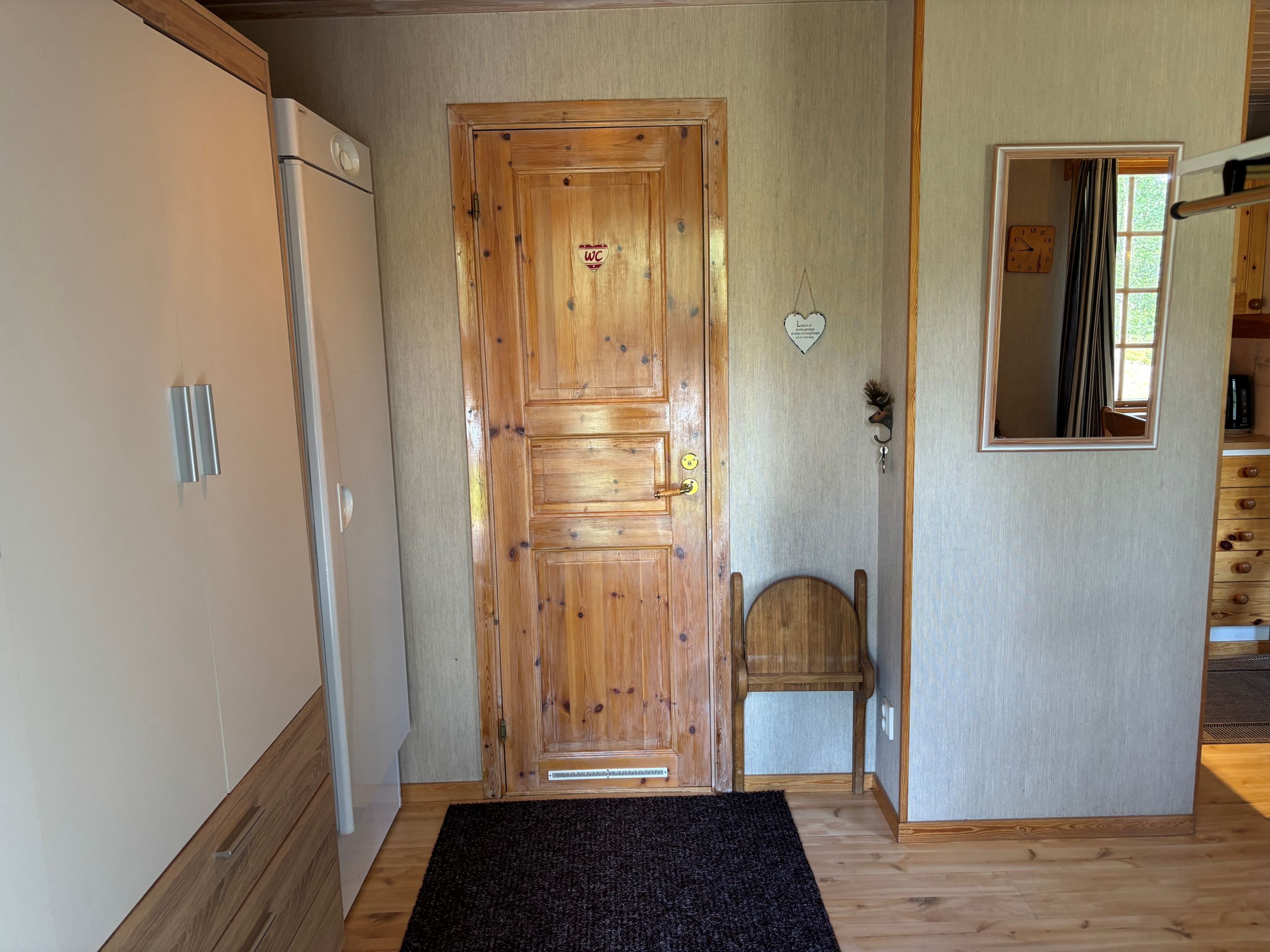 Hall med torkskåp t.v och badrum rakt fram i bild