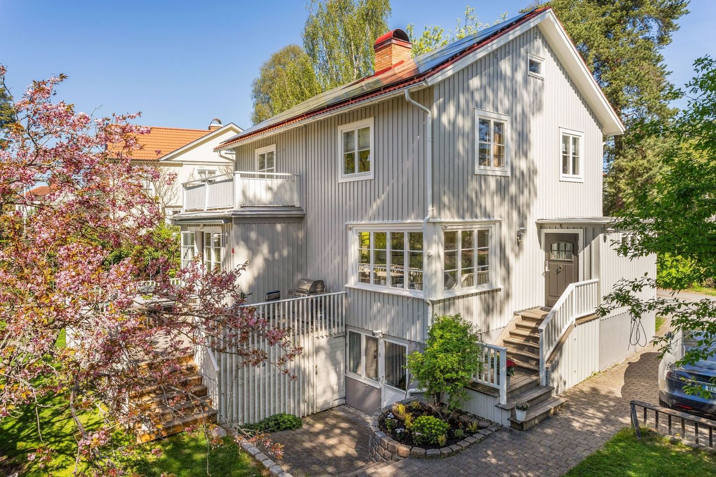 Fint anlagd tomt med stensättningar och grönskande inramning