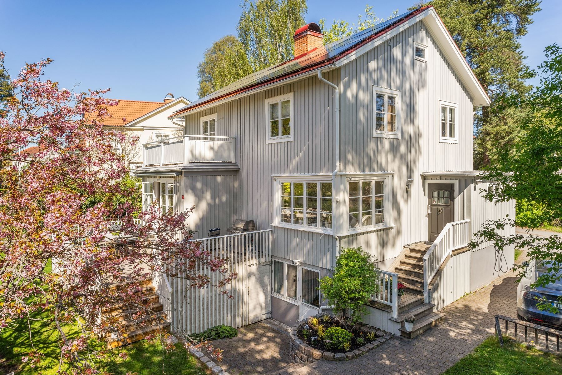 Fint anlagd tomt med stensättningar och grönskande inramning