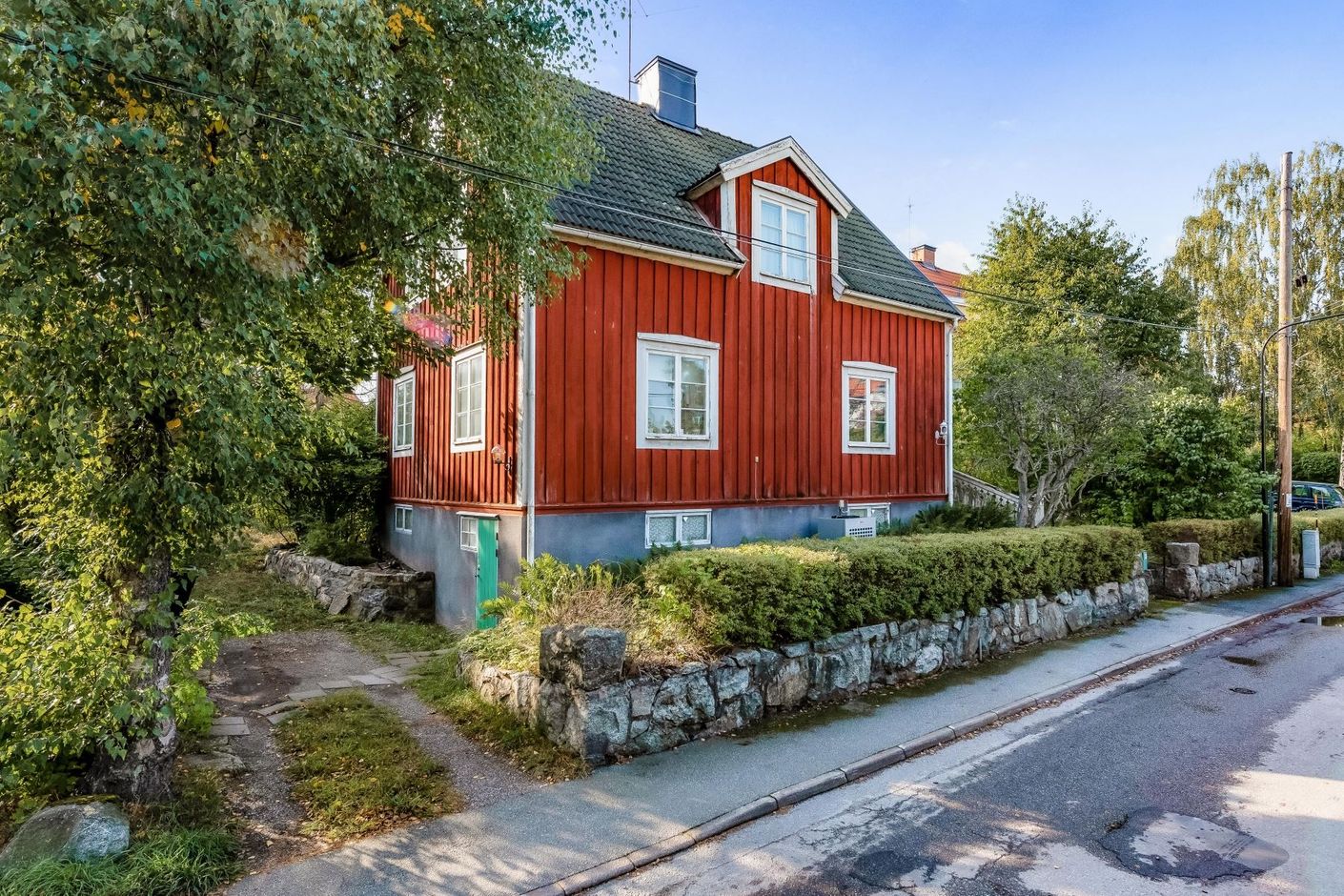 Fin inramning av granitmur och häck med bilplats på tomten