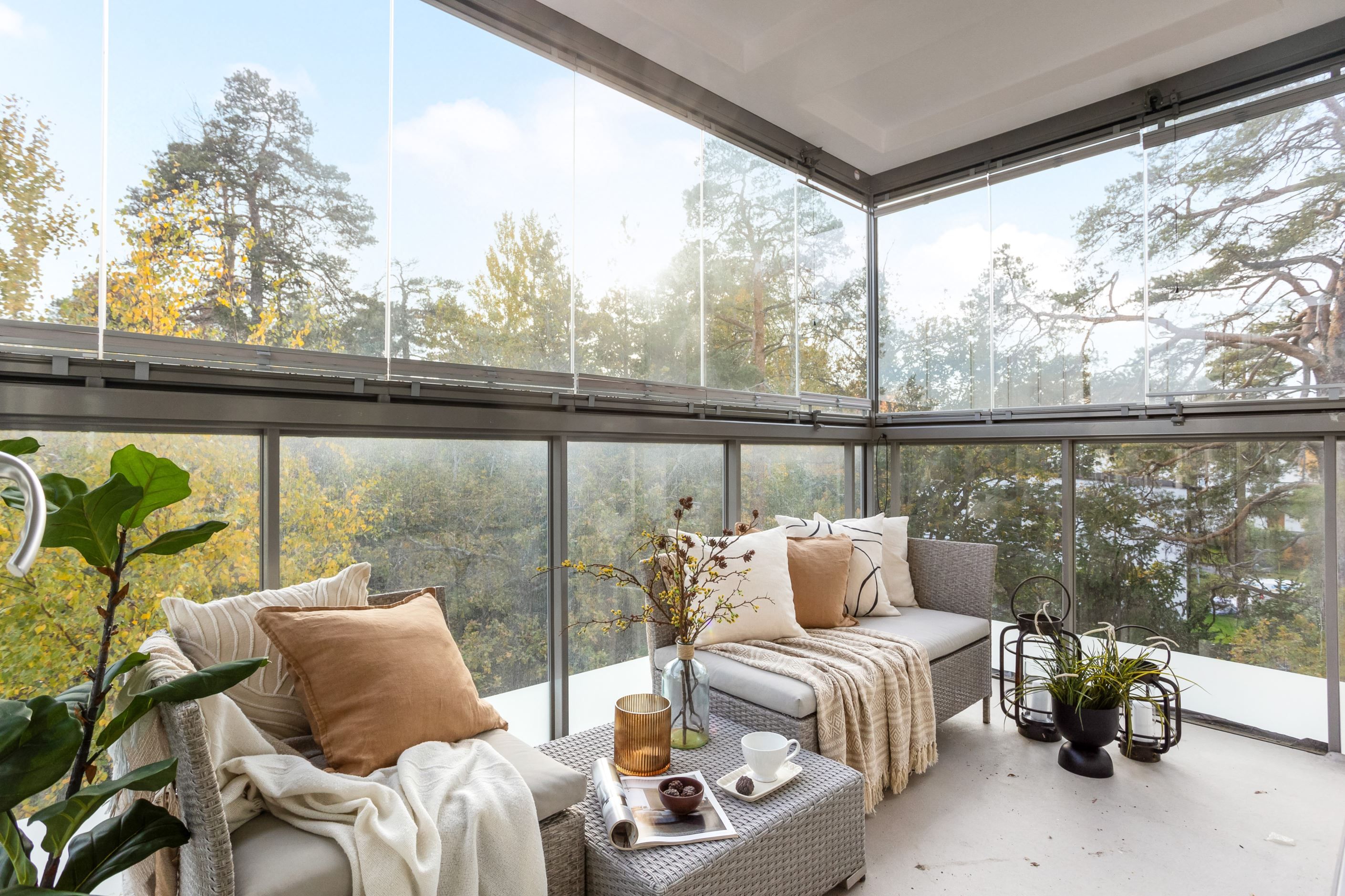 Generös, inglasad balkong mot grönska - ett uterum den varma årstiden