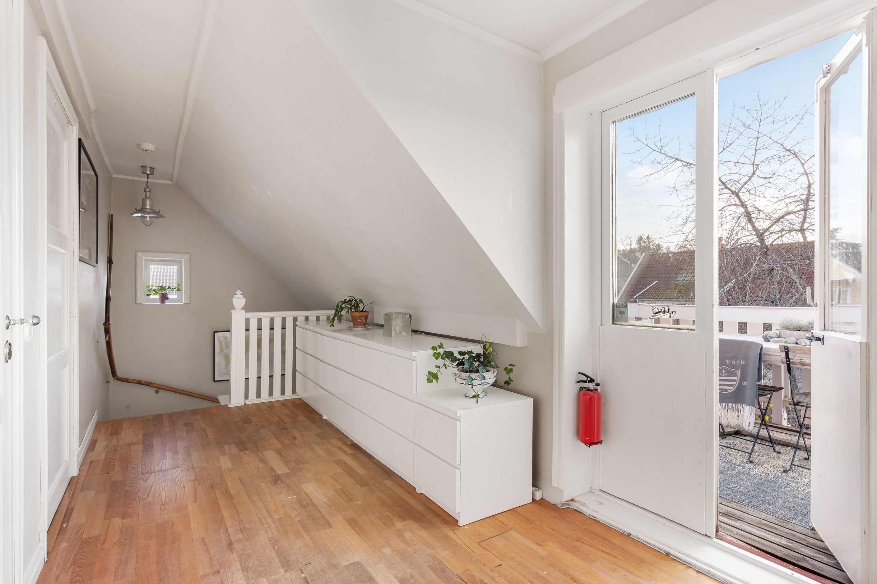 Övre hall med dörr ut mot soldränkt altan