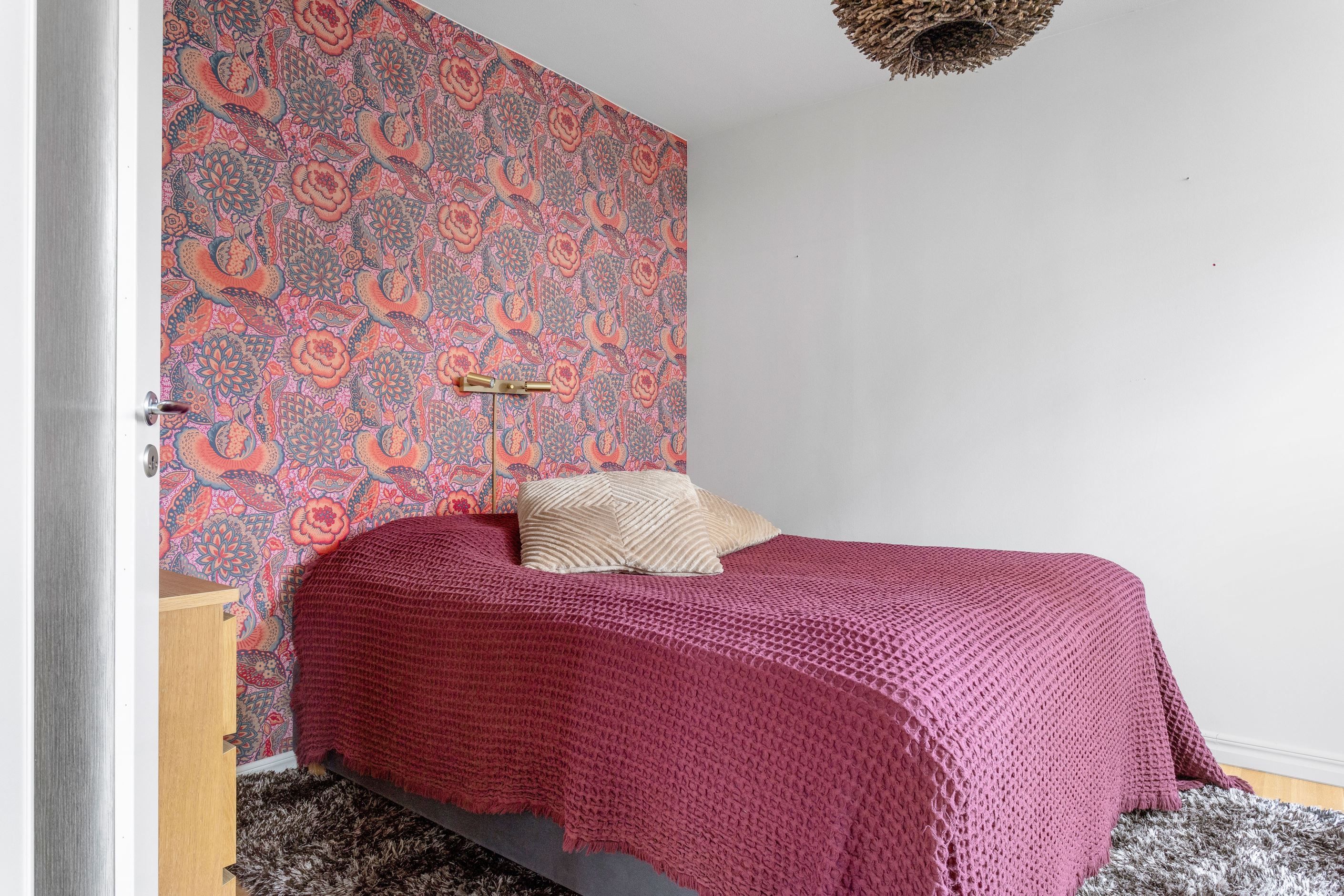 Fondvägg i sovrum som rymmer dubbelsäng samt gott om förvaring i angränsande walk-in-closet