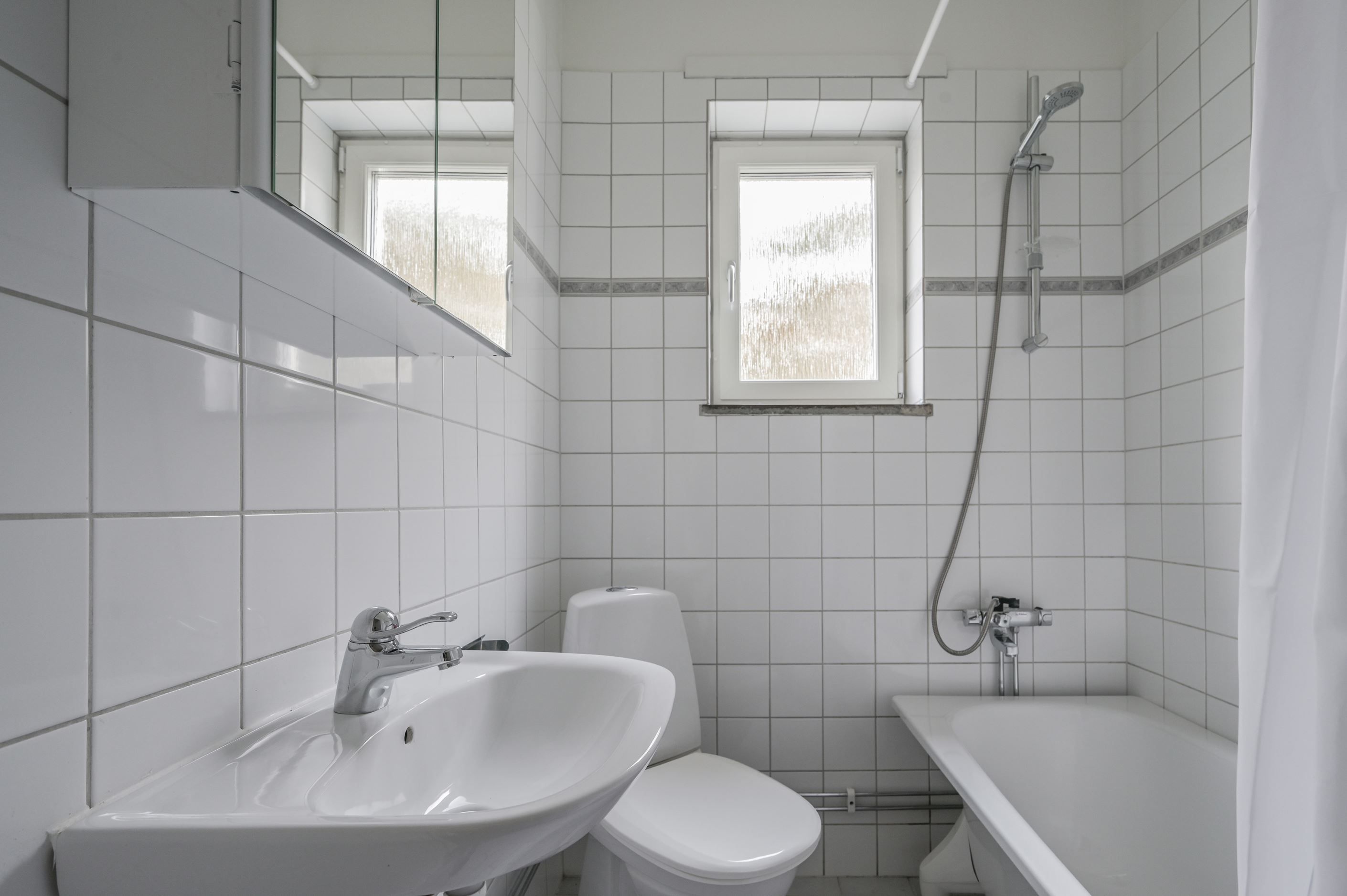 Kaklat badrum med badkar och fönster för trivsamt ljusinsläpp