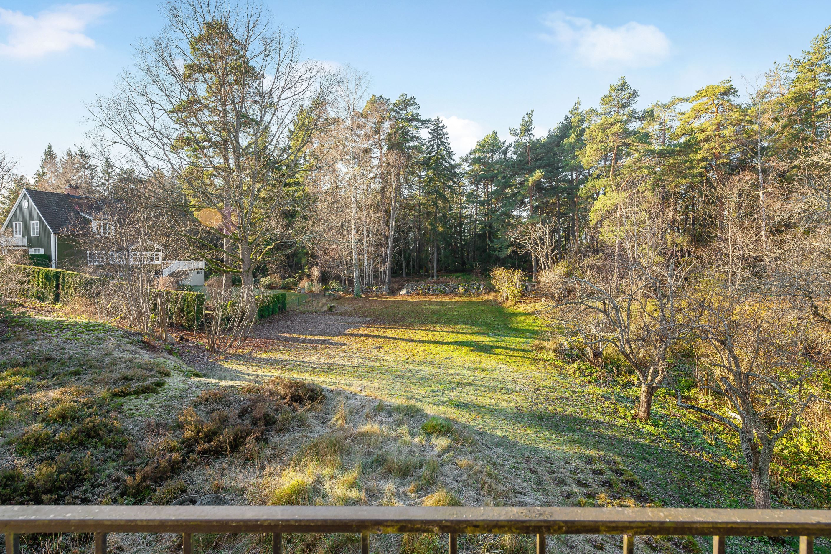 Storslagen vy från huset mot den soldränkta tomten i efterfrågat läge nära Ålstens Torg