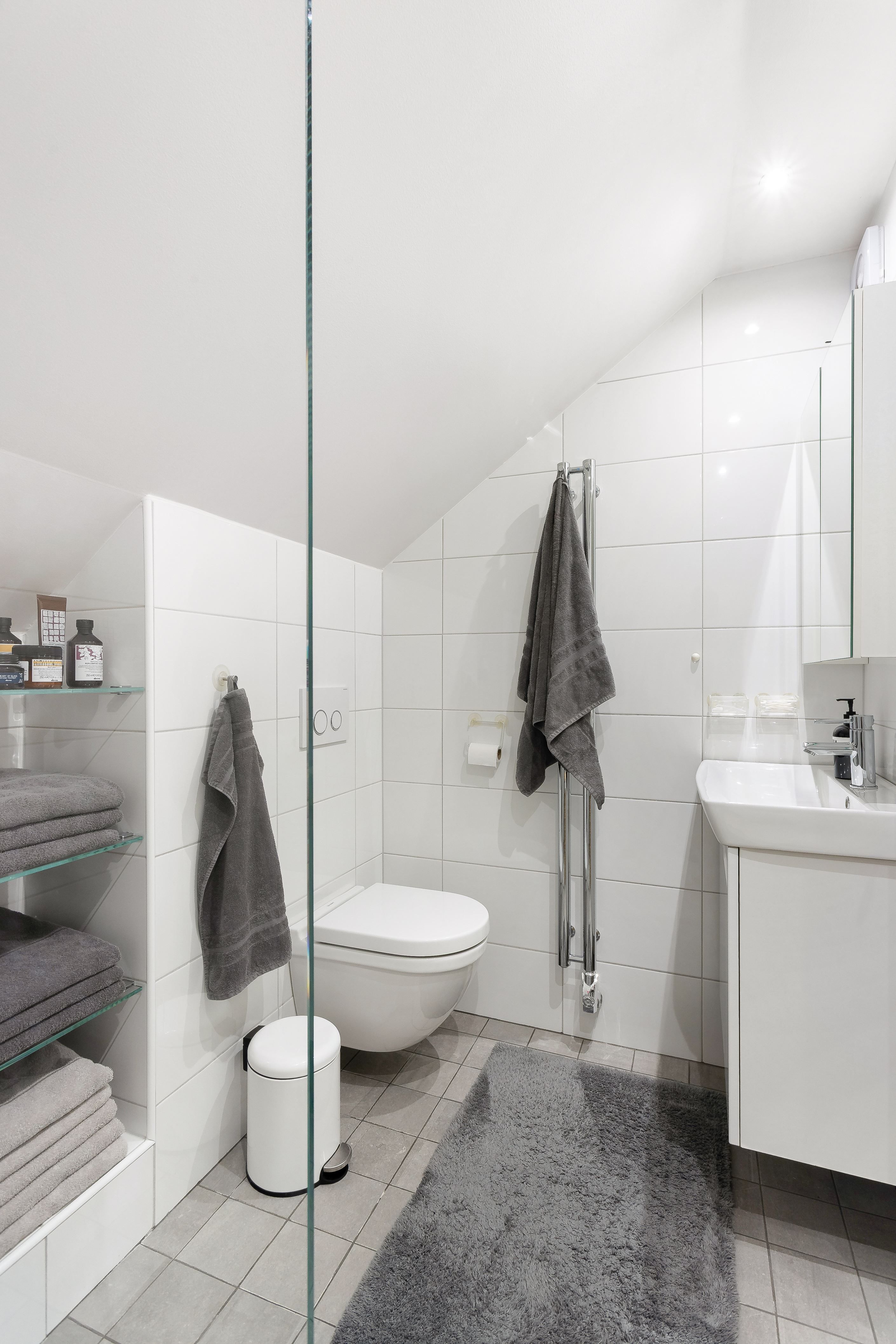 Helkaklat badrum på övre plan med vägghängd WC och platsbyggd förvaring