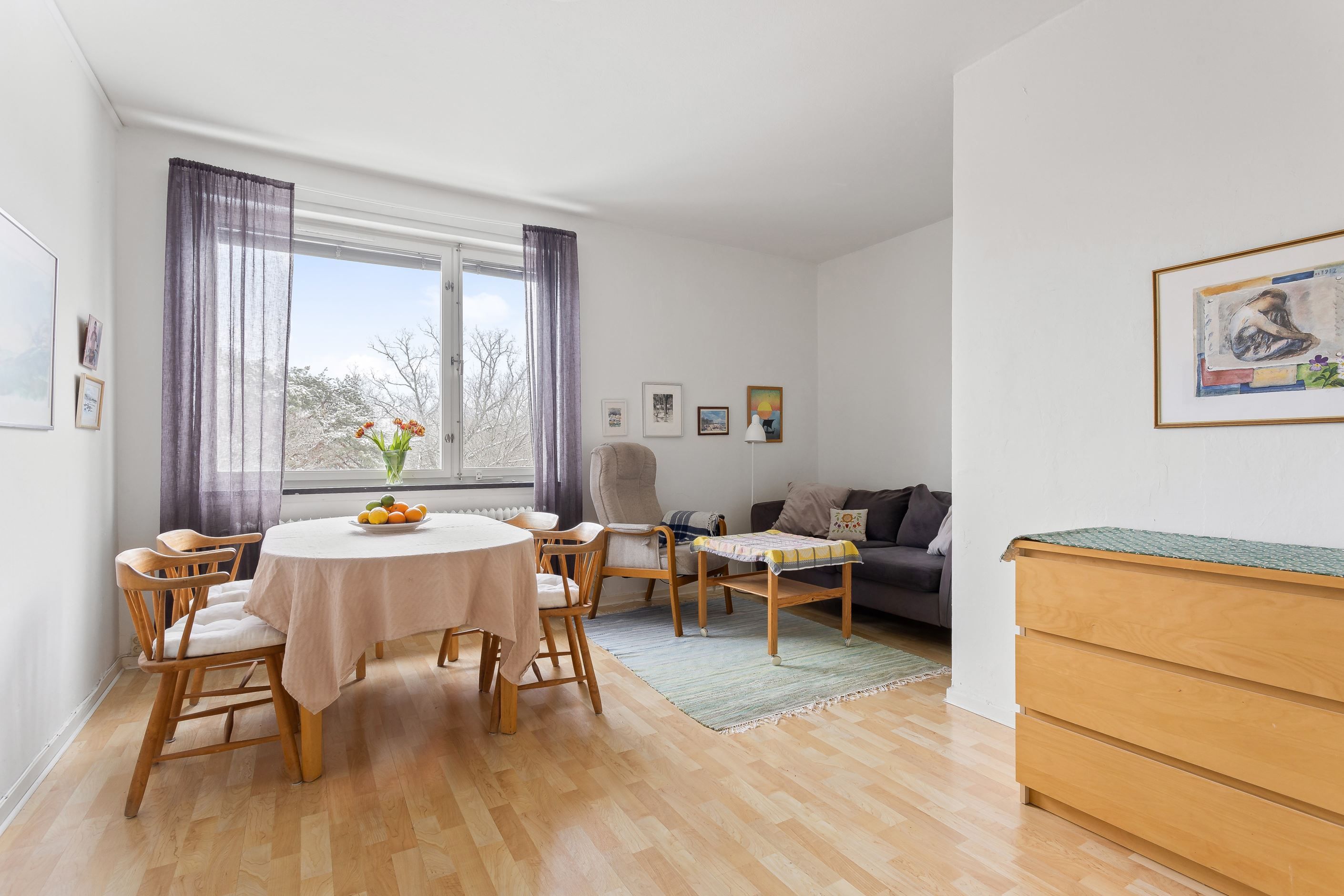 Vardagsrum med plats för soffa samt matplats invid väl tilltaget fönsterparti