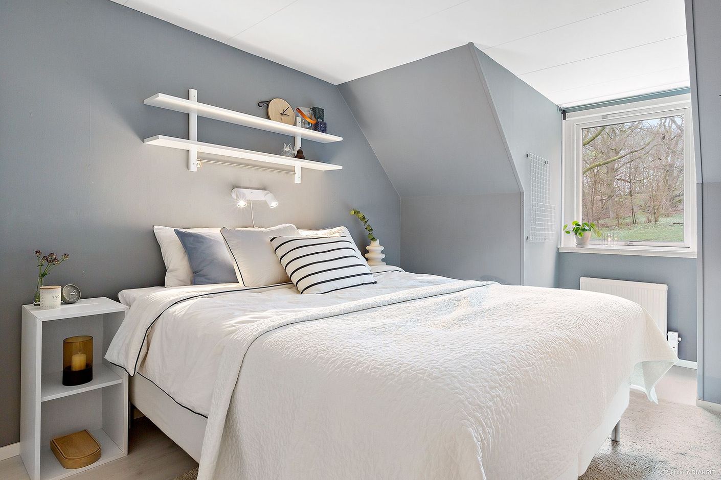 Insynsskyddat rymligt sovrum med utsikt mot bokskogen.