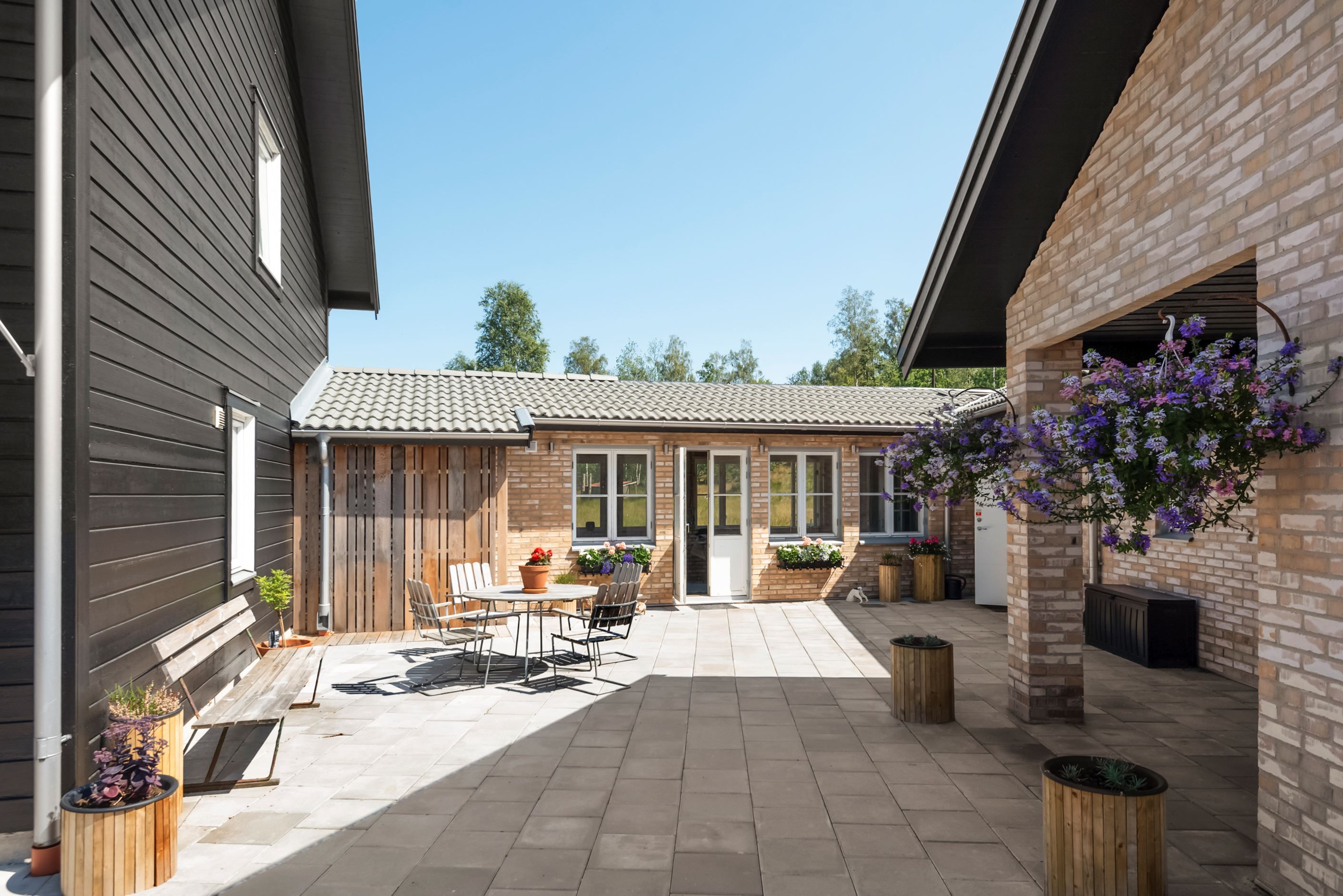 Vid entrén är en av husets alla uteplatser med orangeriet bakom.