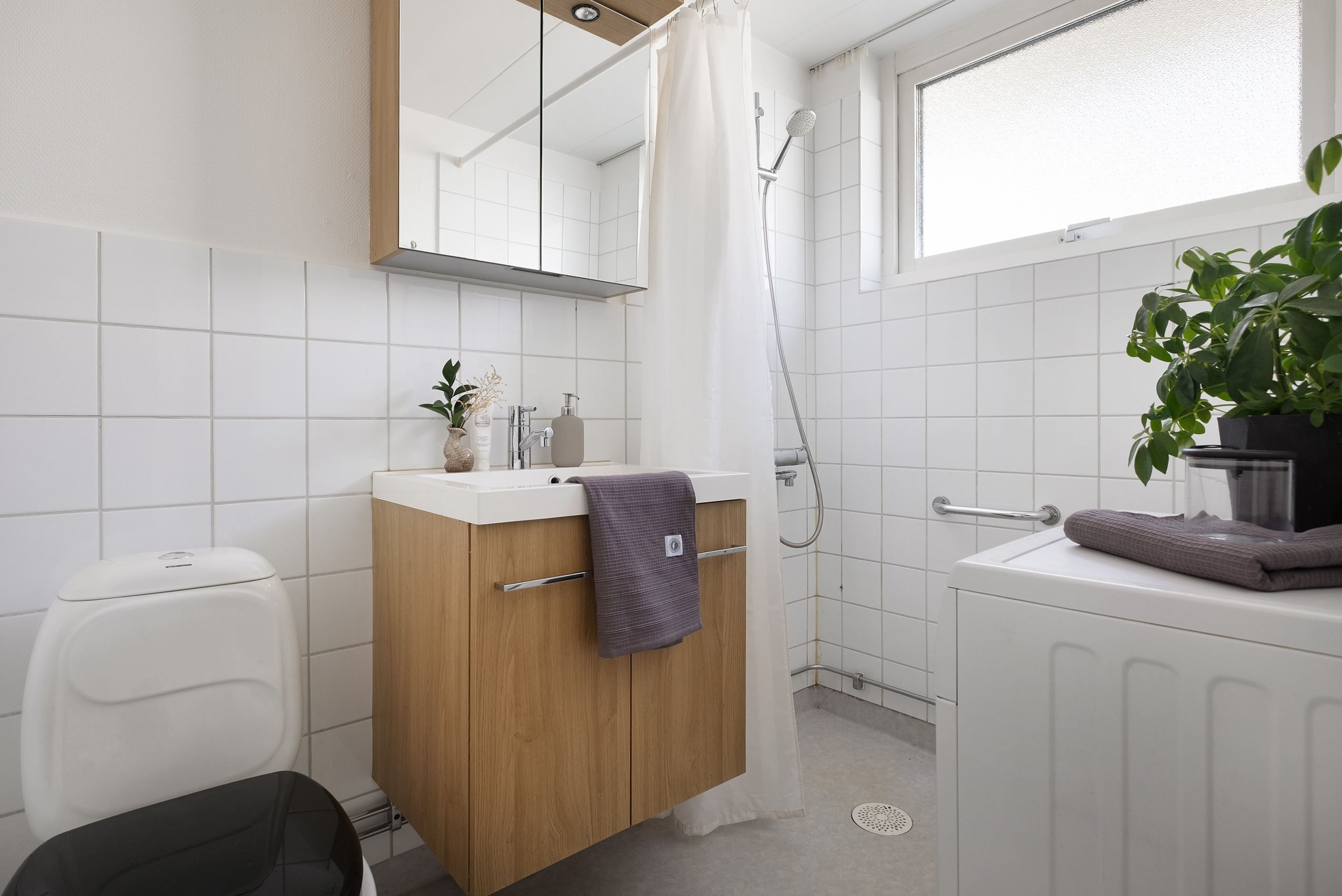 Det delvis kaklade badrummet har fönster, dusch och tvättmaskin.