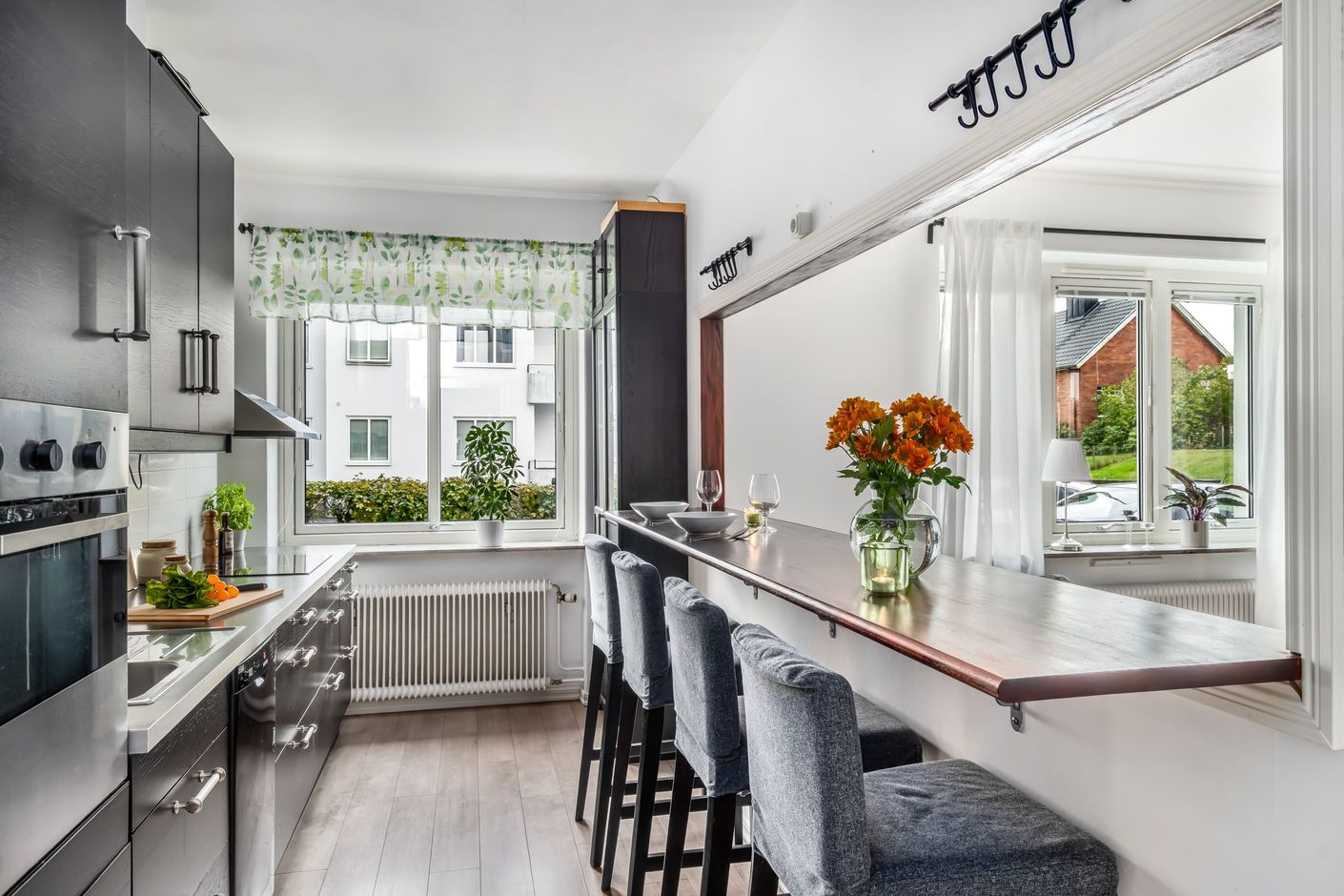 Modernt kök med stilrena detaljer och en praktisk bardisk mot vardagsrummet.