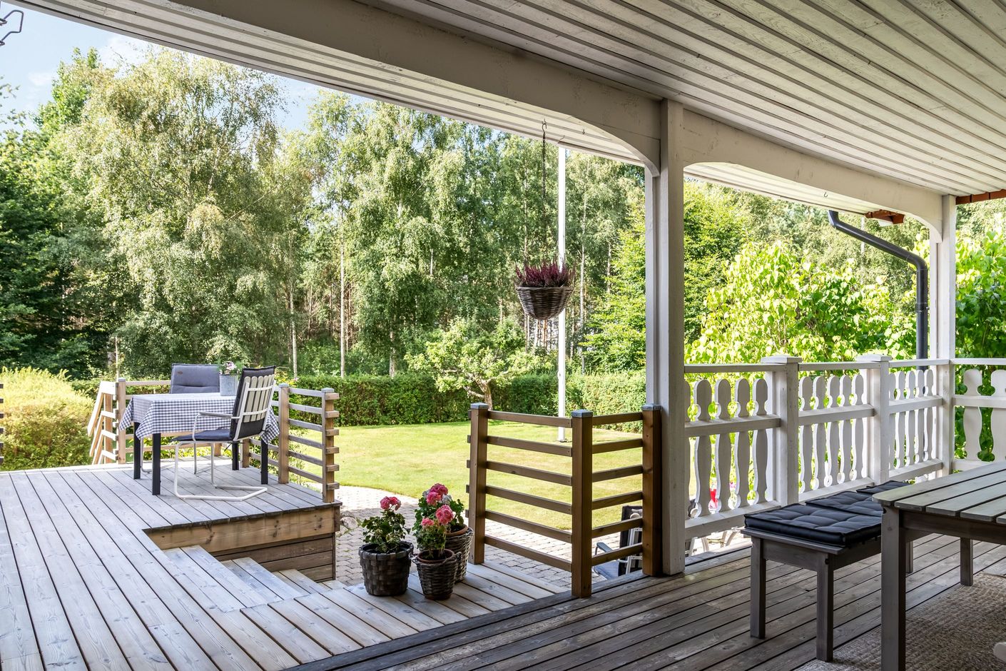 Den generösa delvis överbyggda altanen vetter mot en insynsskyddad trädgård.