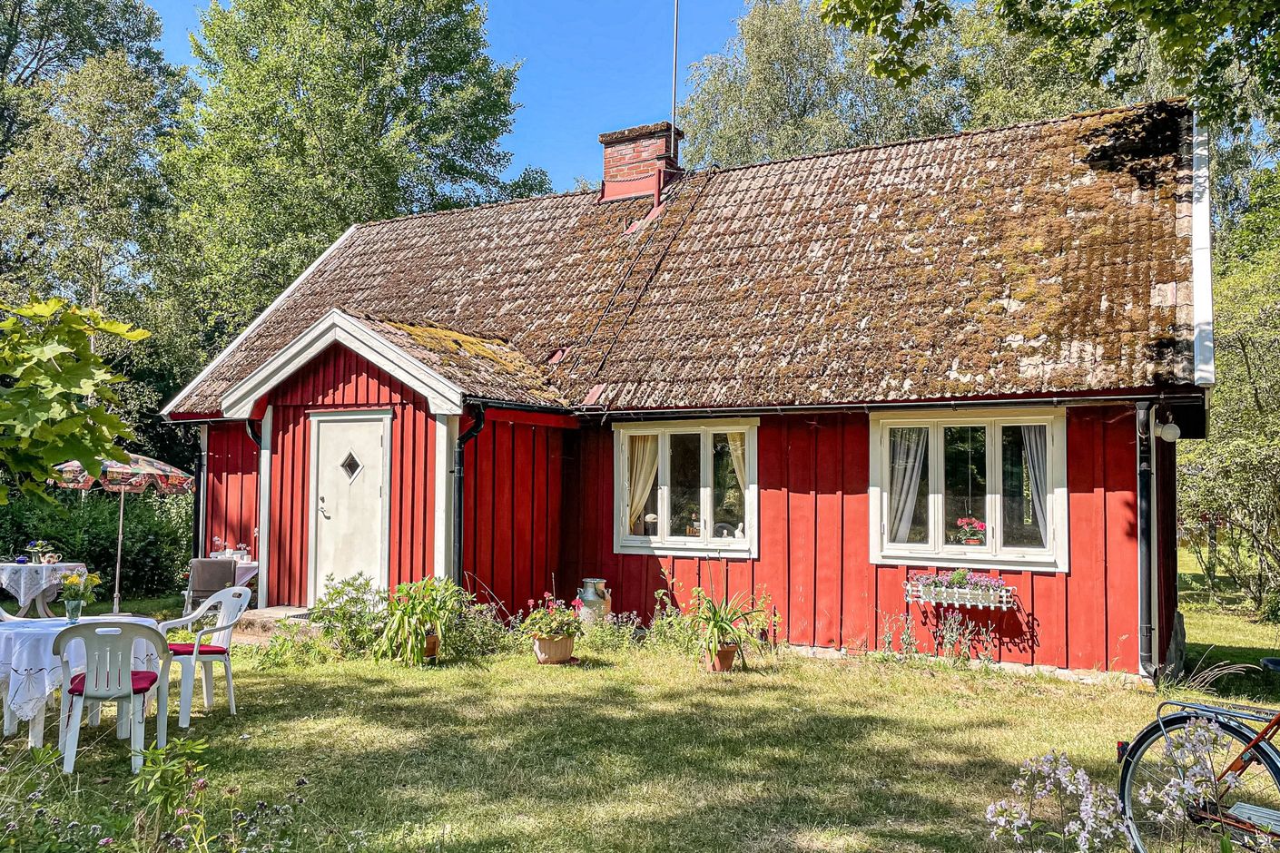 Det charmiga torpet smälter in i miljön med sin röda färg och vita detaljer