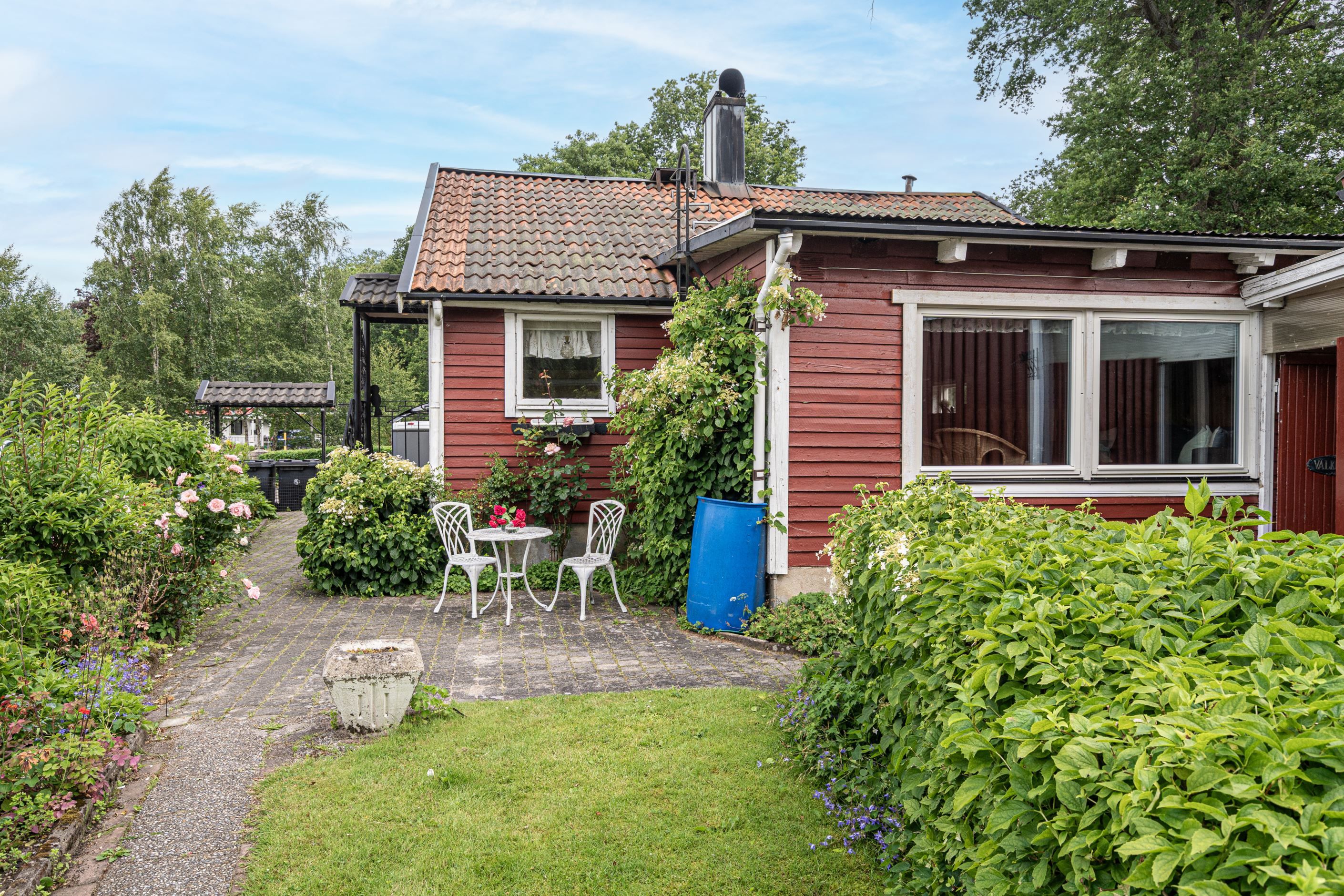 Uteplats bland prunkande rabatter vid entrén till annexet