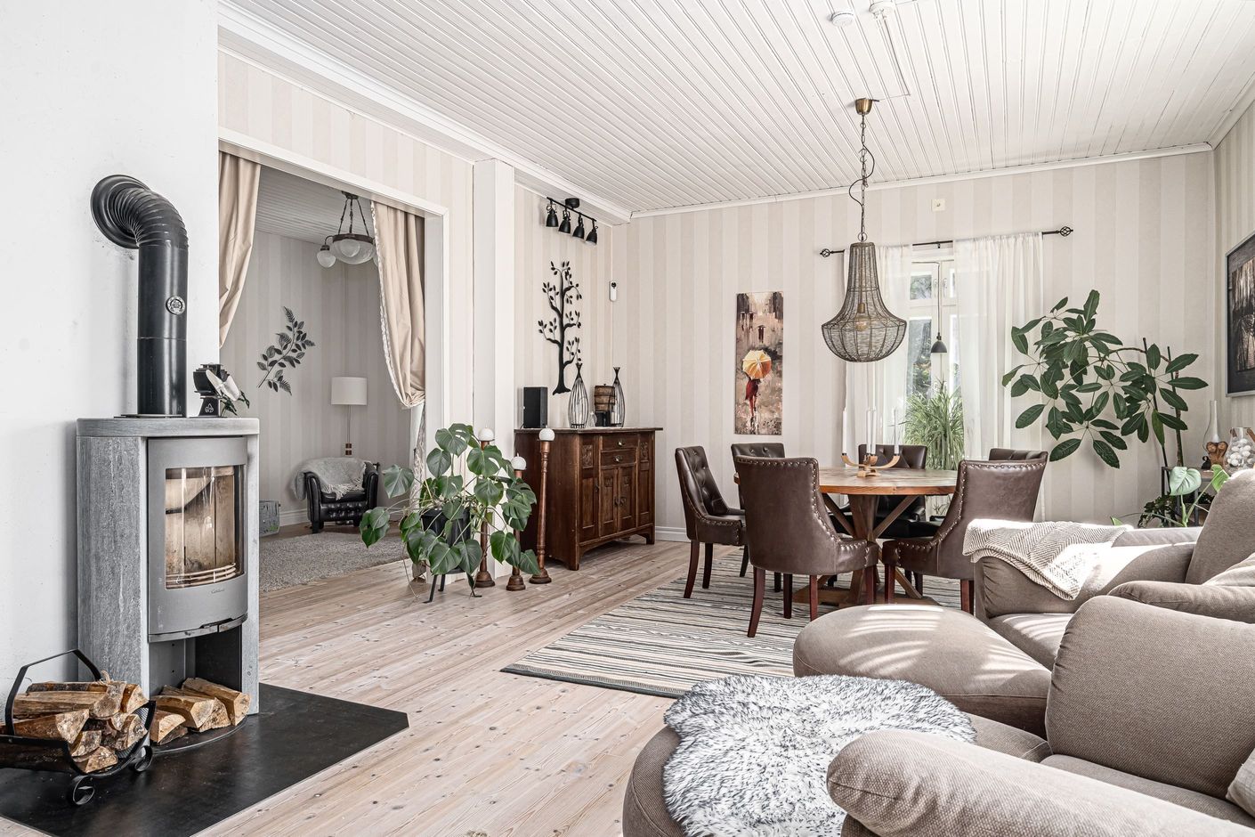 Stort öppet vardagsrum med en av husets värmande täljstenskaminer