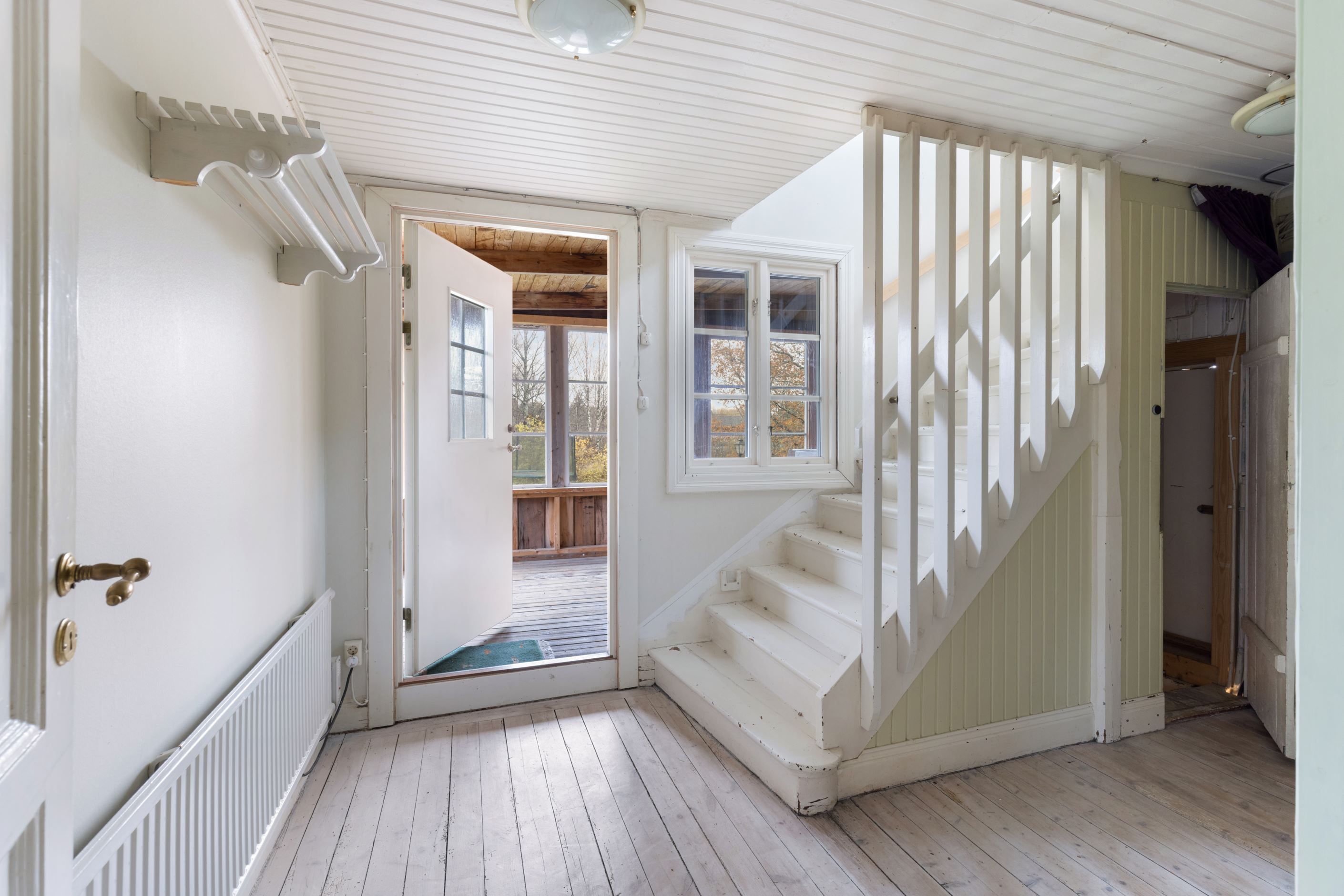 Hall och trappa till övre plan samt utgång till veranda