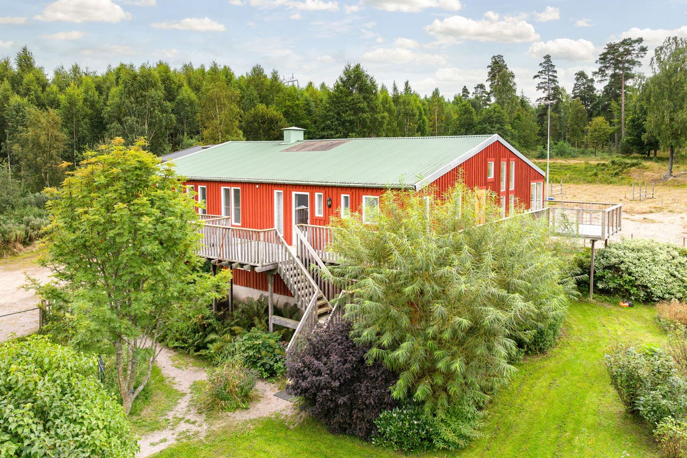 Stall med lägenhet ovanpå, bakom syns en tidigare ridbana med belysning