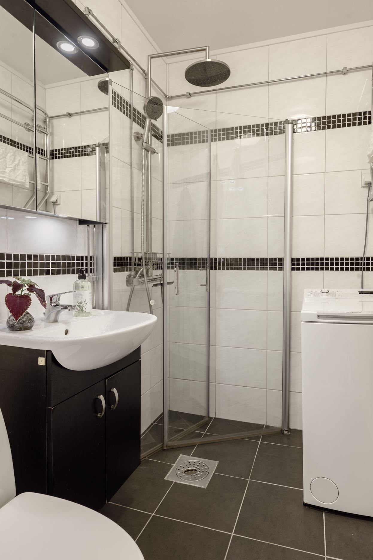 Helkaklat badrum med duschhörna och tvättmöjligheter.