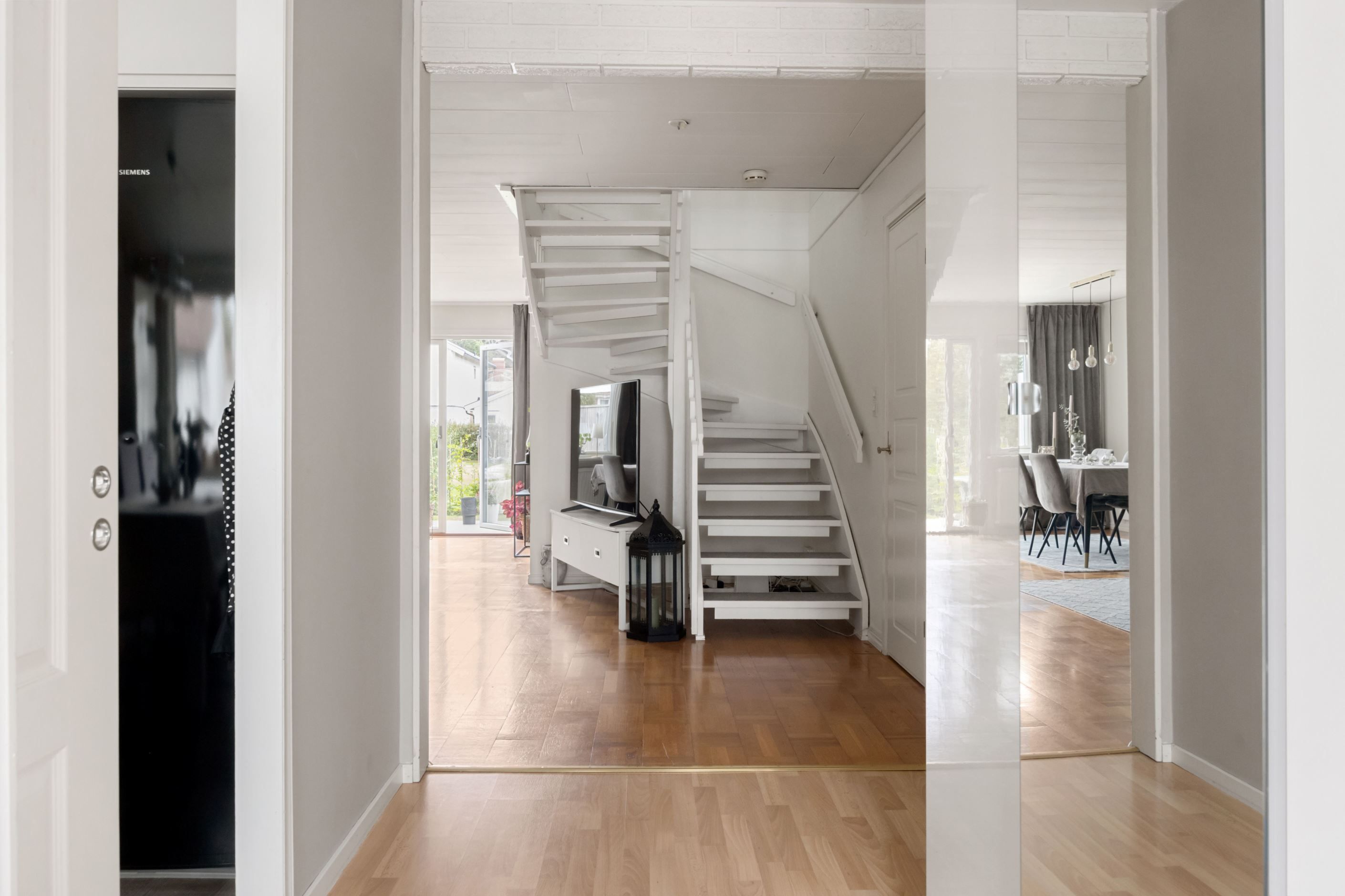 Vy från hall mot vardagsrum och utgång till trädgård och altan.