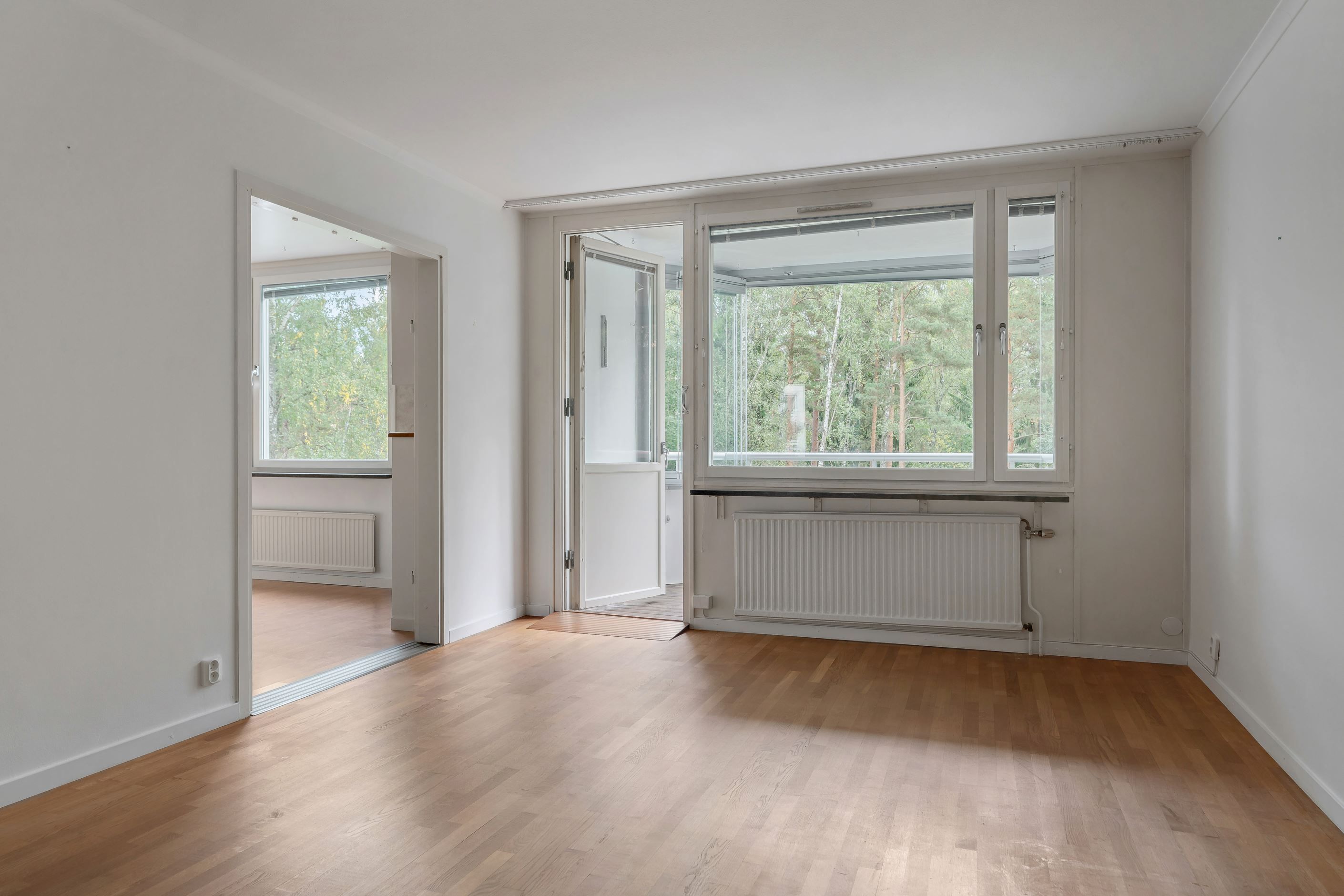 Vältilltaget vardagsrum med utgång till bostadens inglasade balkong