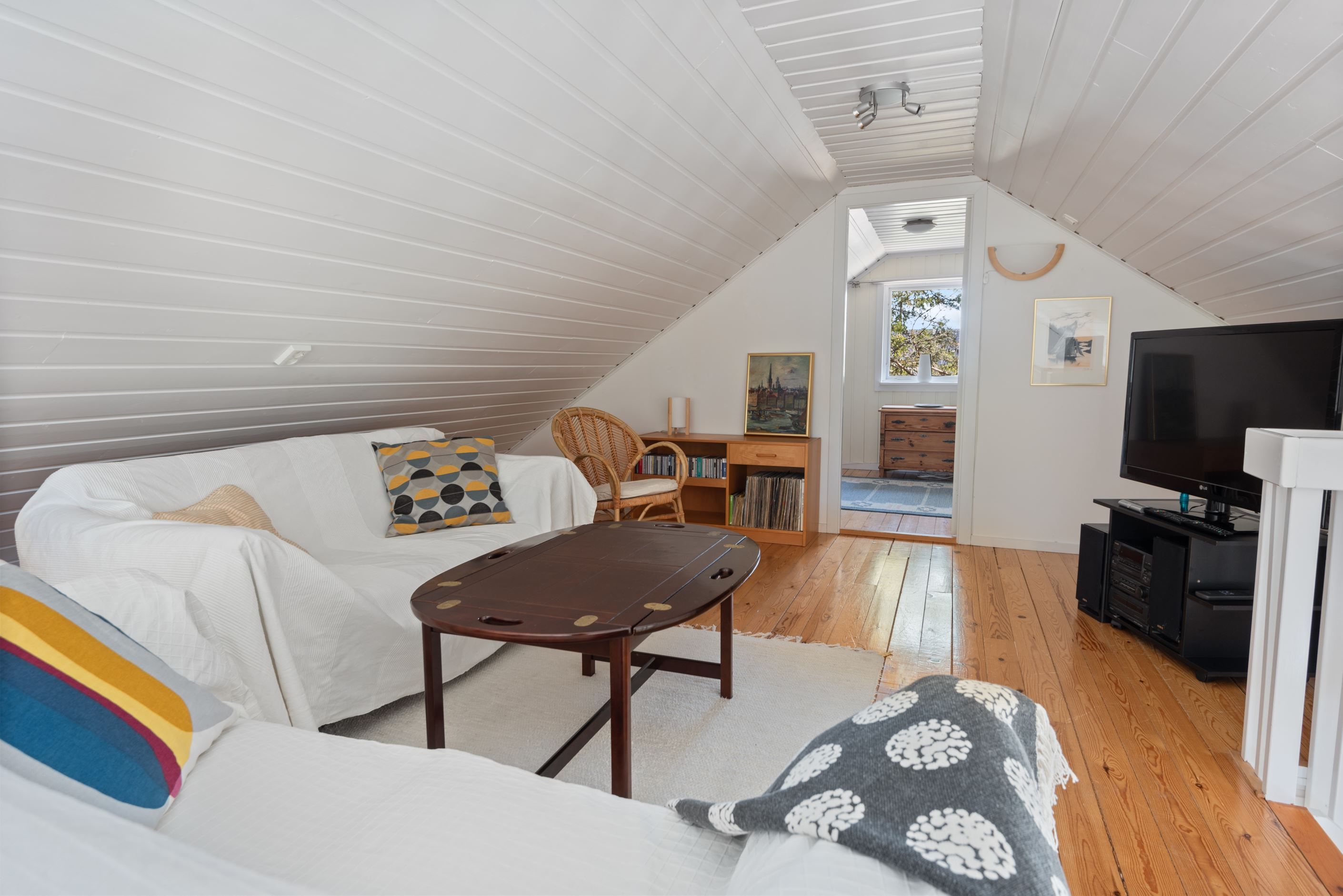 Övre plan i form av loft med ståhöjd bestående av allrum, sovrum och förvaring i kattvind.