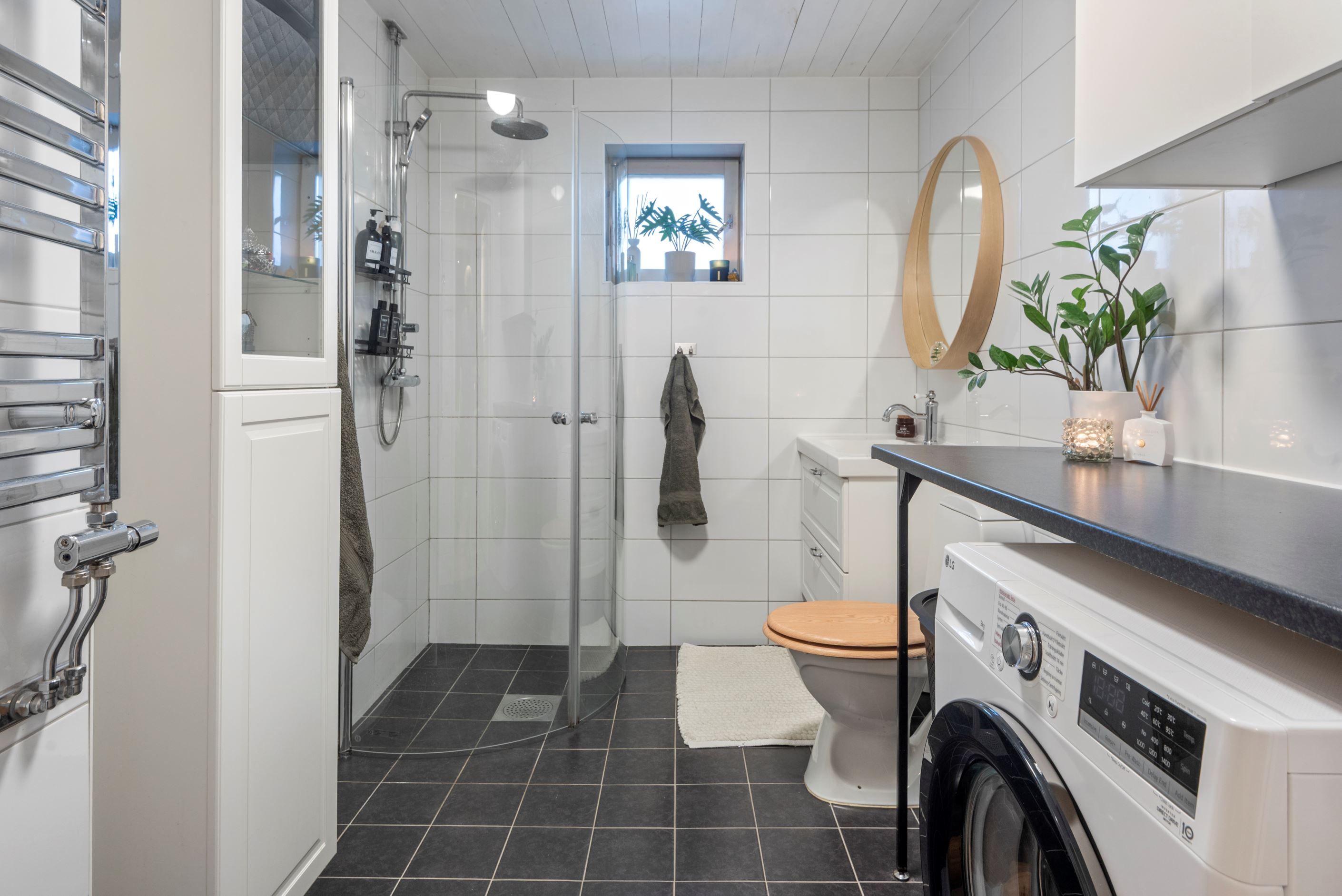 Helkaklat badrum med tvättmaskin och arbetsbänk.