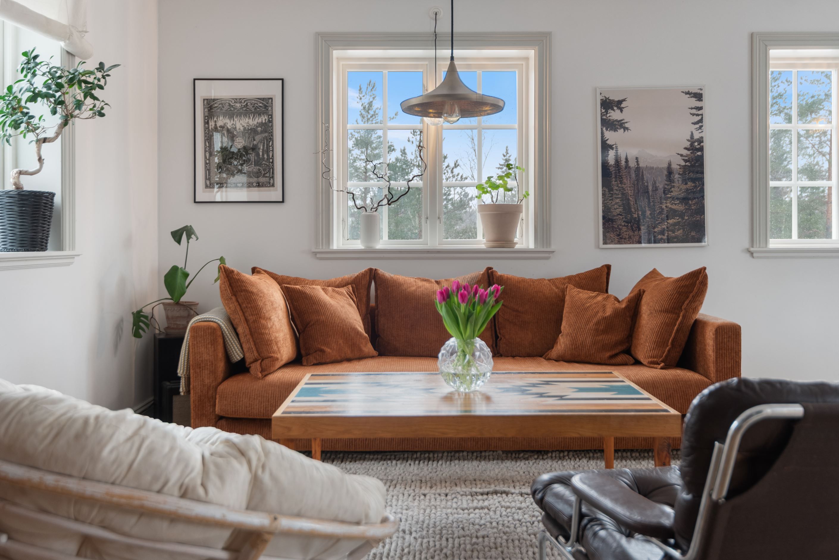 Stort umgängesrum med plats för soffgrupp, matbord och fönster i tre väderstreck.