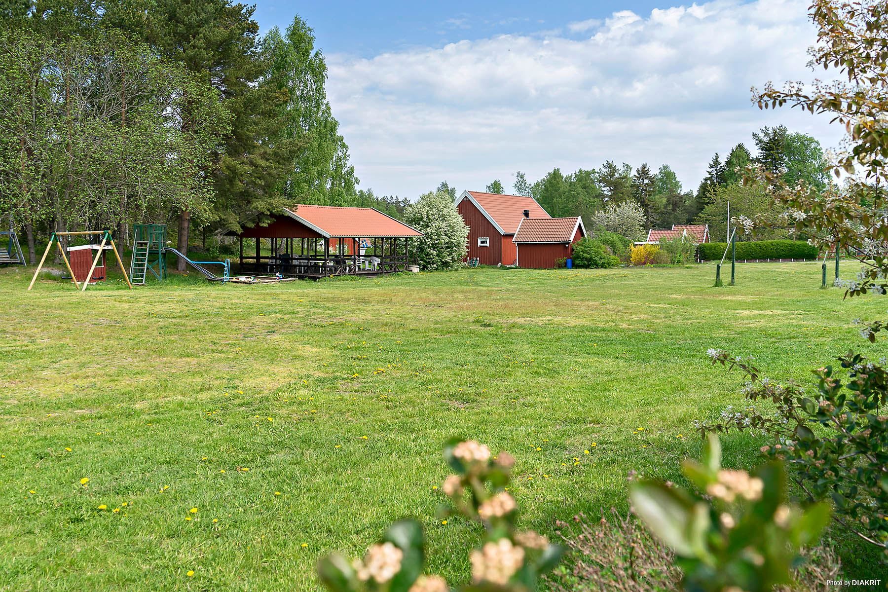 Stor äng med lekplats och sittgrupper under tak