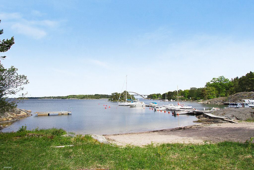 Båtbryggor och strand i havet. Djuröbron i bakgrunden!