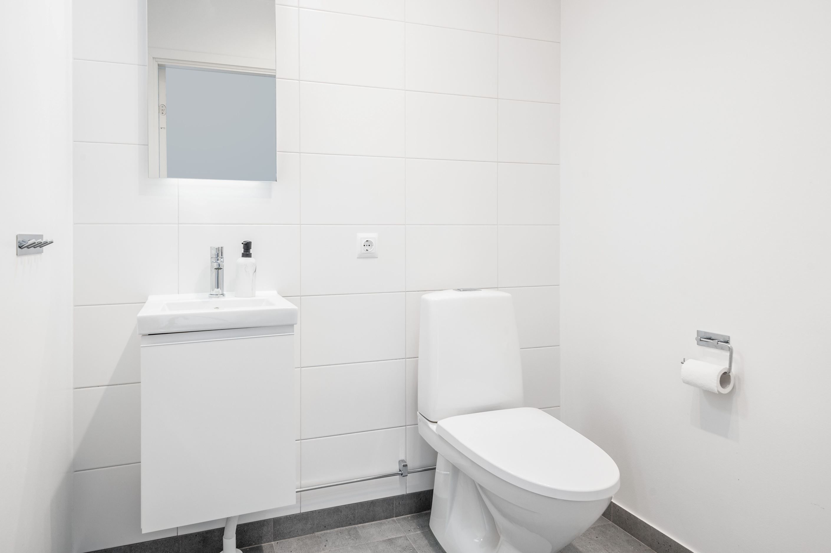 Gäst-WC med klinkergolv, kaklade väggar och kommod.