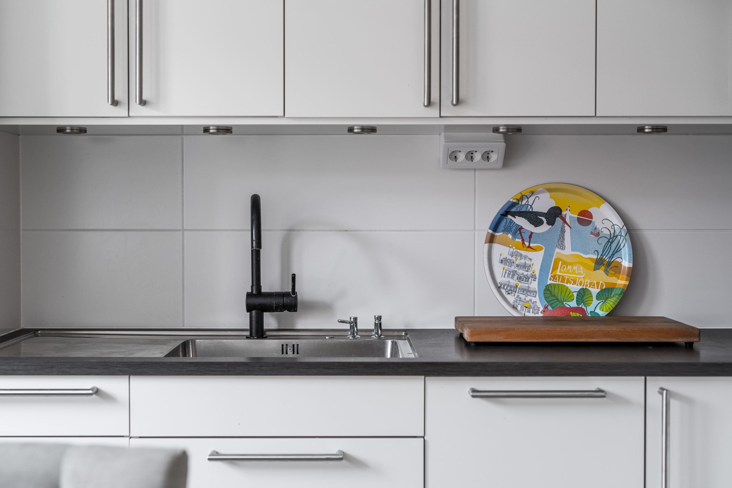 Mörk bänkskiva och vitt kakel ovanför