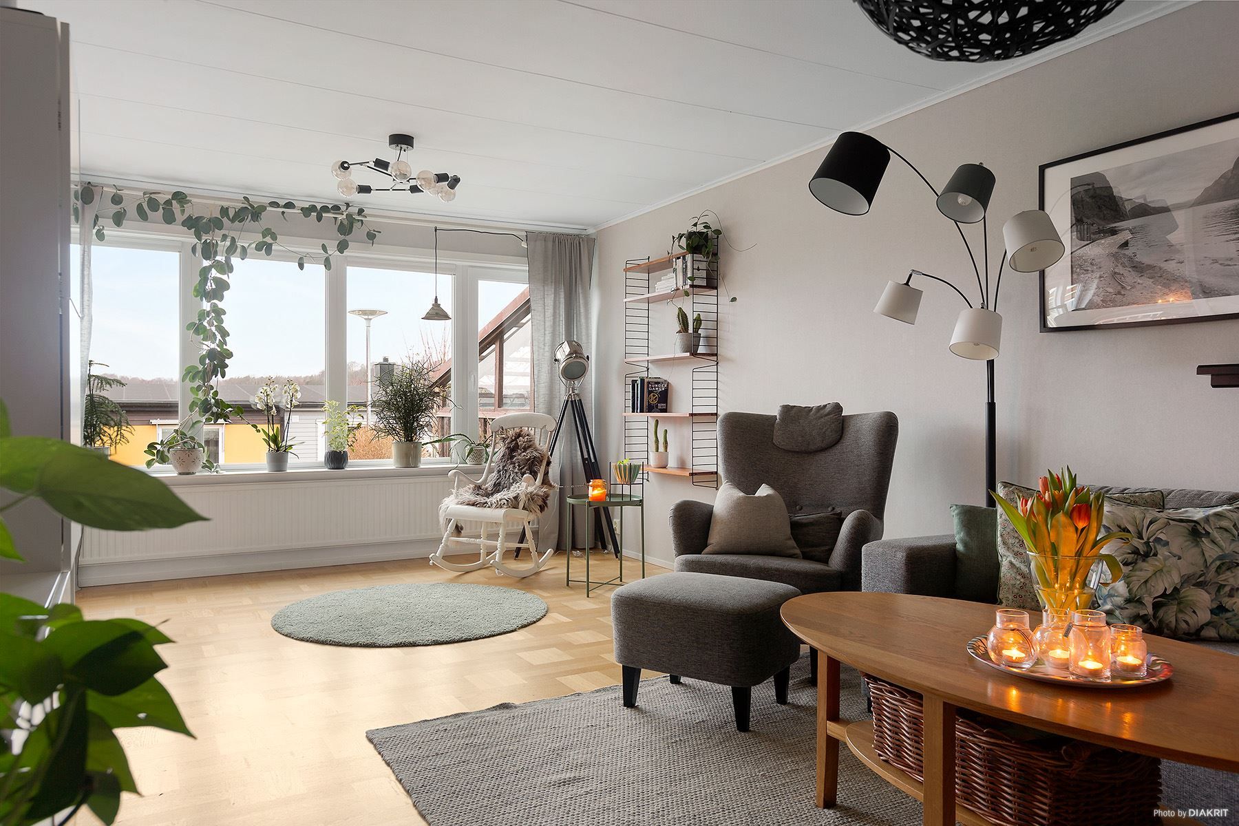 Ljust vardagsrum med fönster längst väggen ut mot trädgården