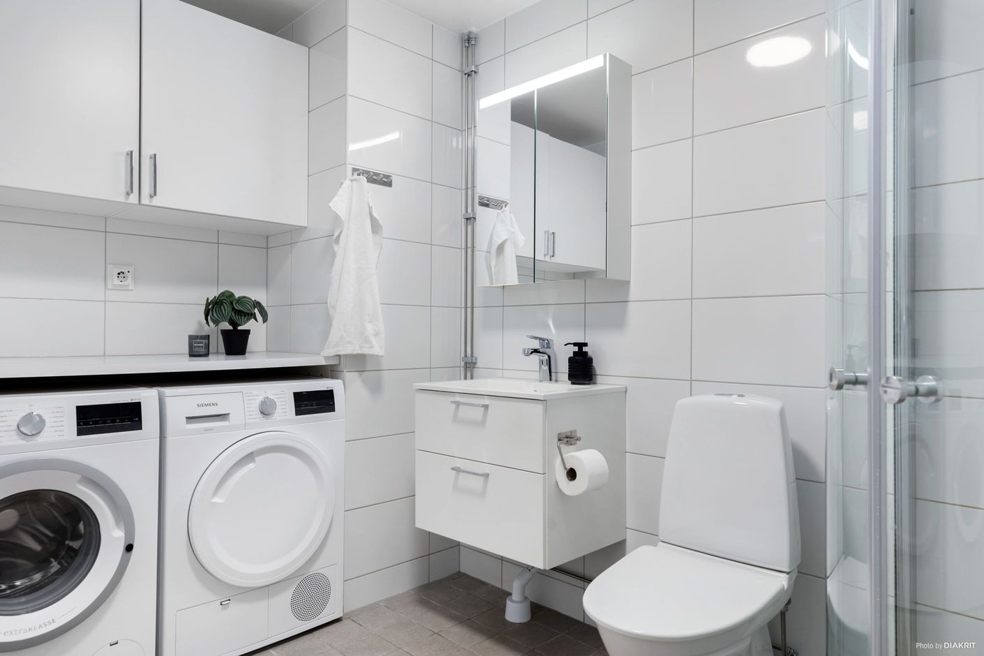 Helkaklat badrum med tvättmaskin och torktumlare