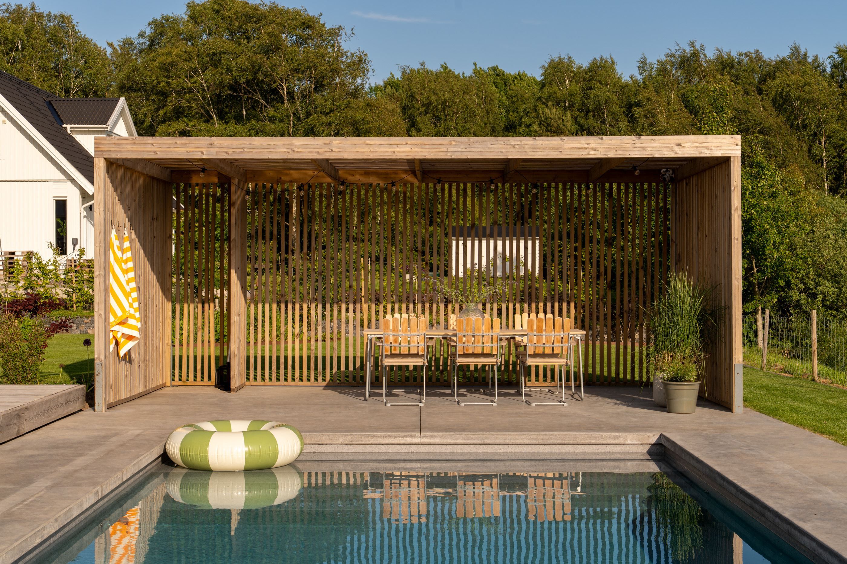 Pergola med matplats intill poolen