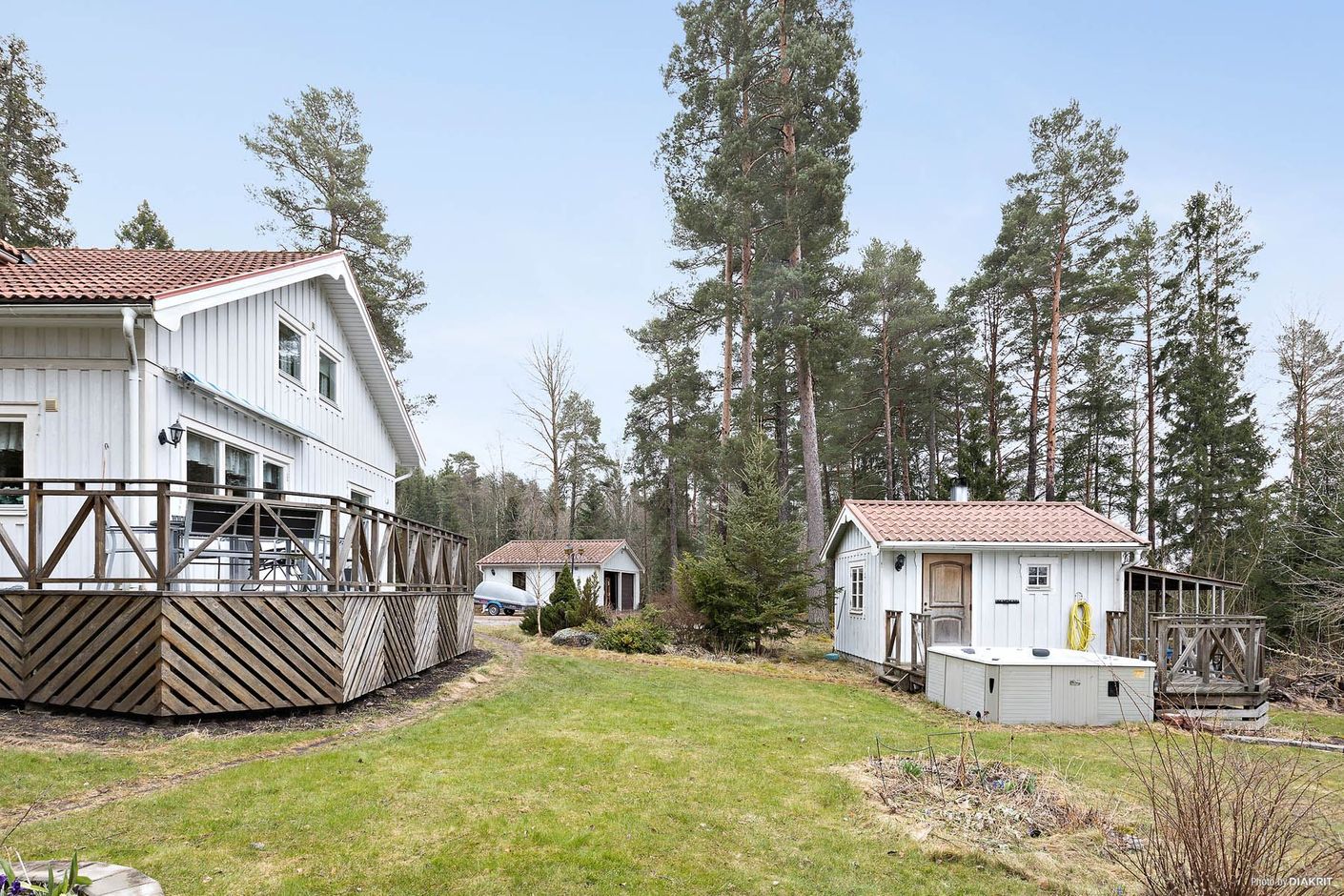 Trädgård mot bastuhus med dusch samt dubbelgarage