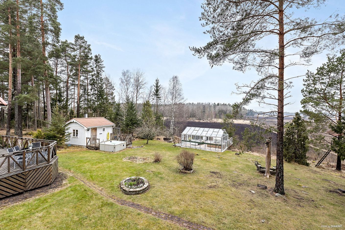Trädgård mot bastuhus och växthus
