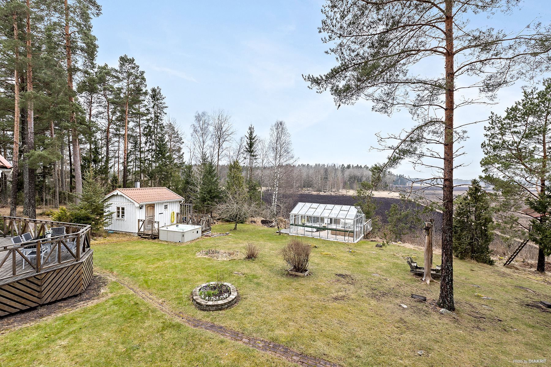 Trädgård mot bastuhus och växthus