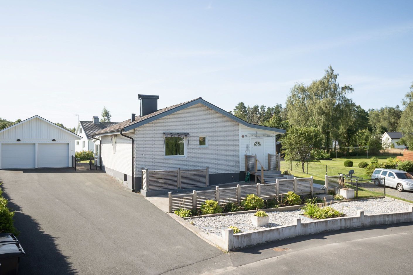 Nyare dubbelgarage och asfalterad parkering.