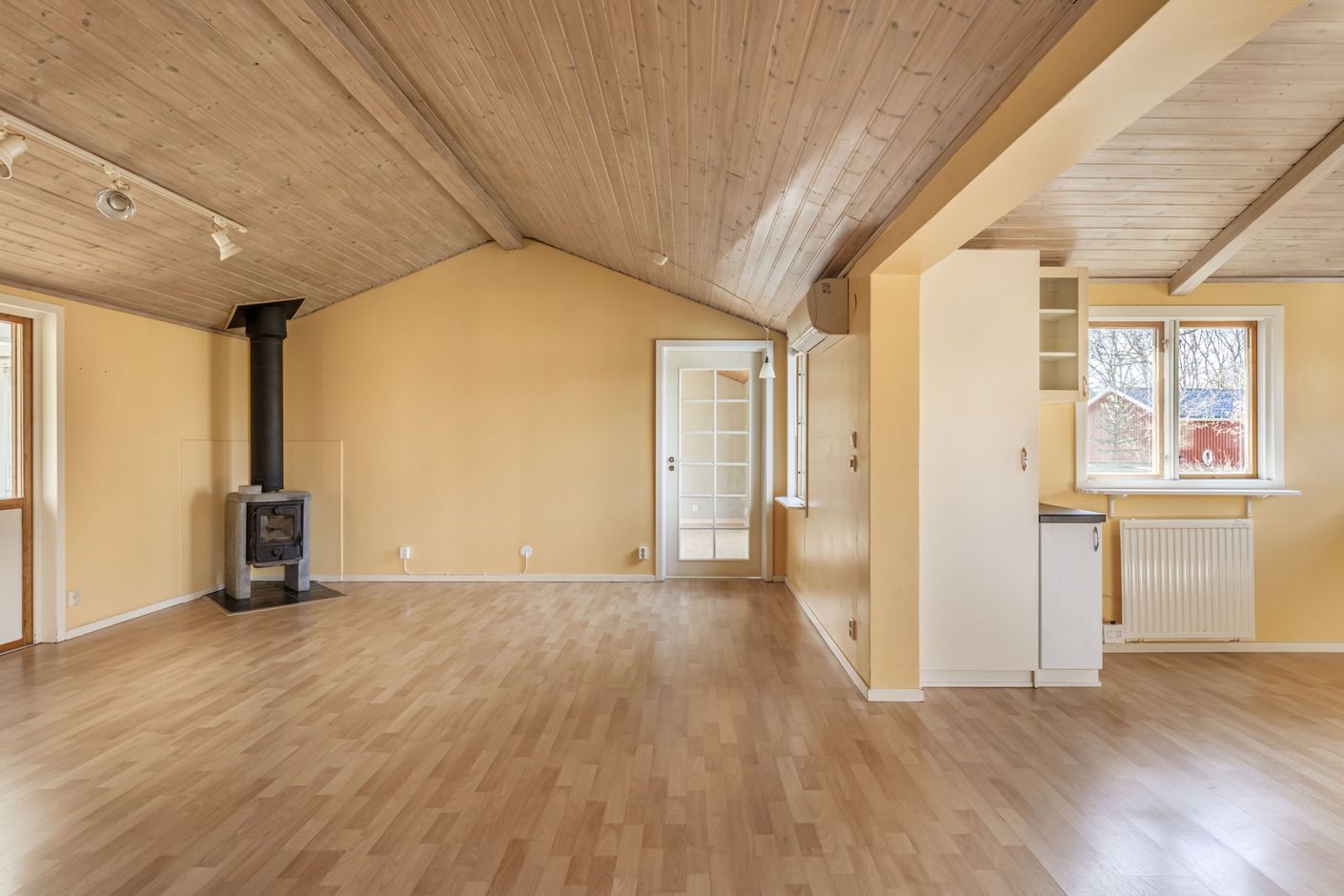 Vardagsrum med öppen planlösning till köket och en trivsam braskamin