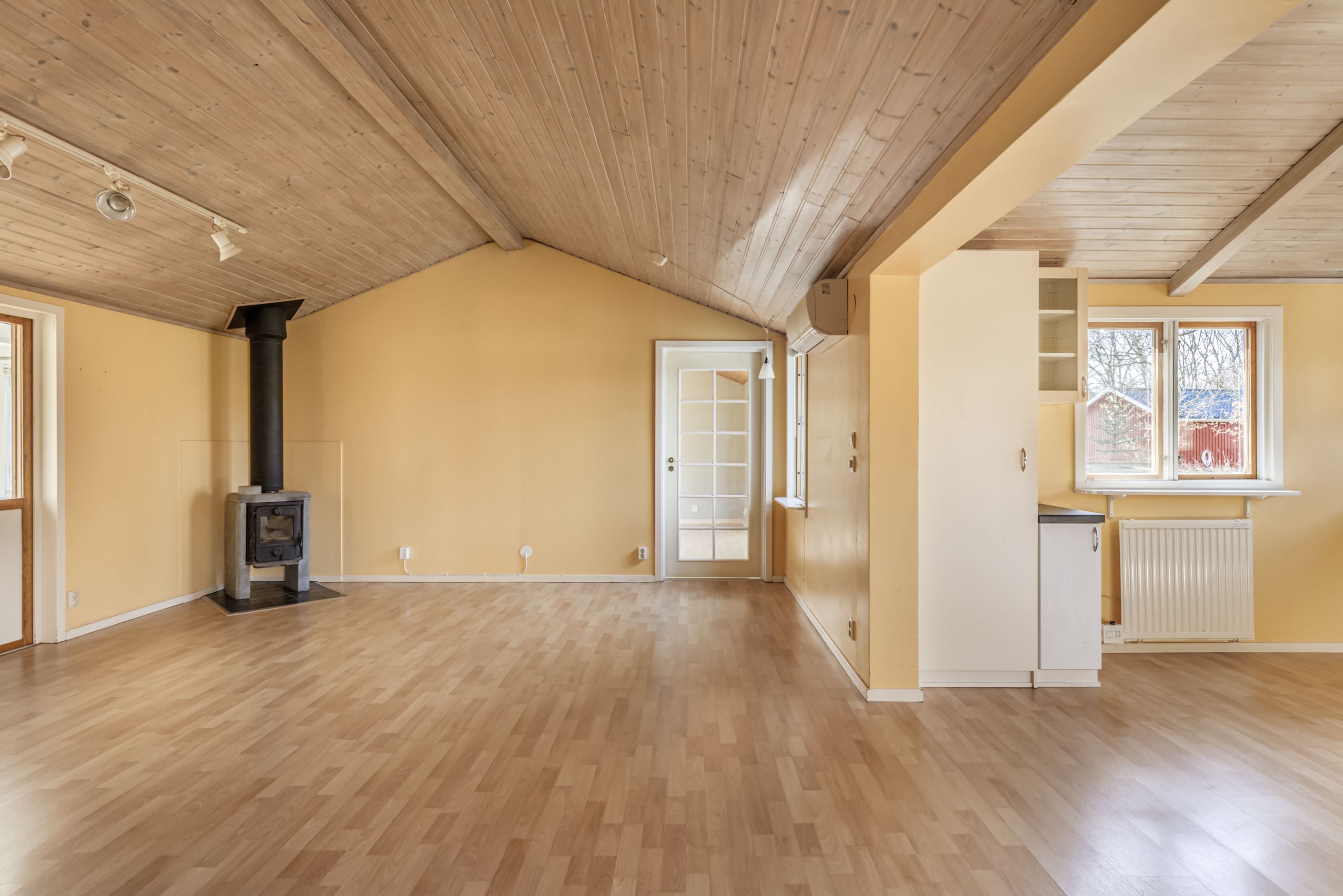 Vardagsrum med öppen planlösning till köket och en trivsam braskamin