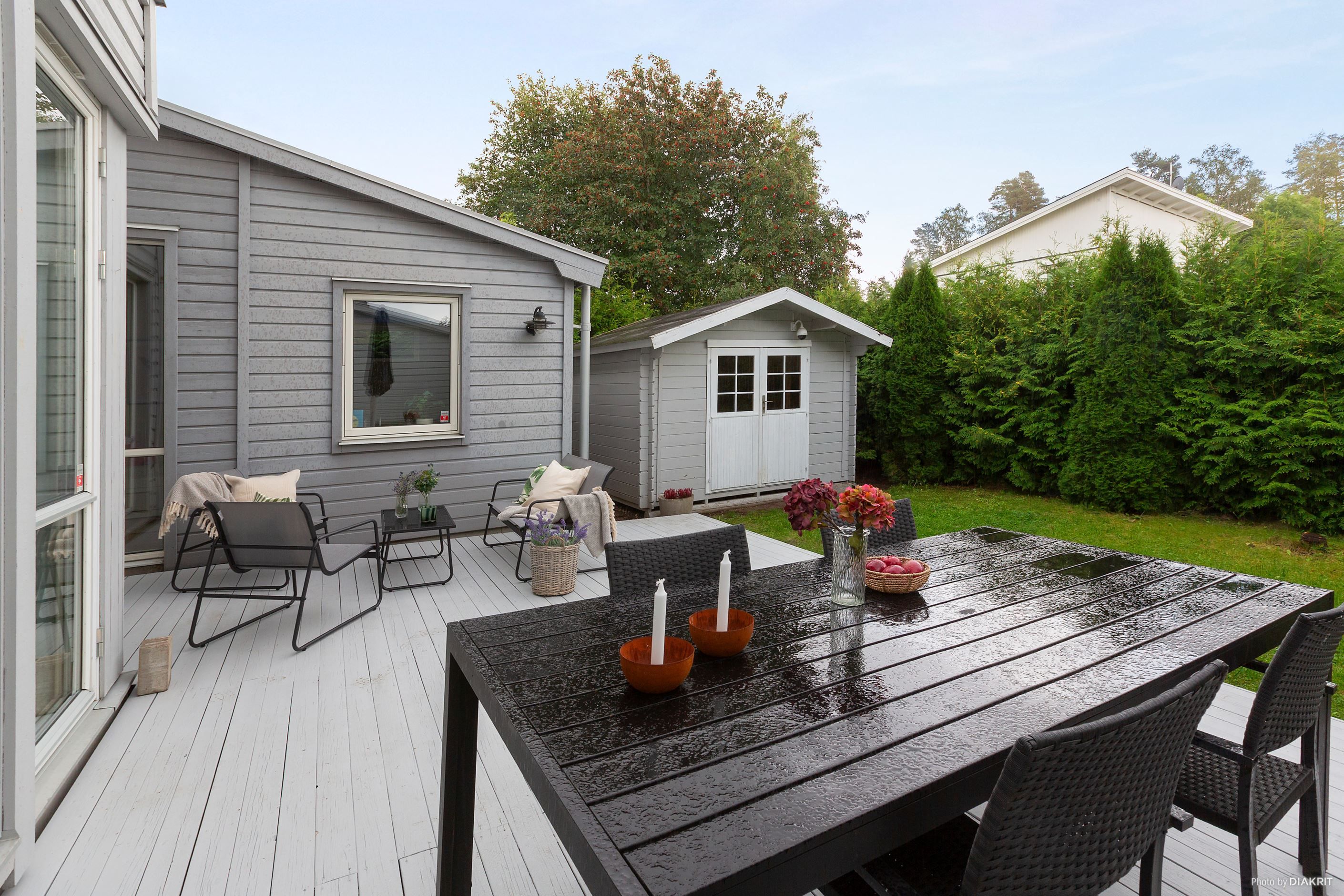 Trädäcksförsedd altan/uteplats med plats för såväl matgrupp som loungegrupp