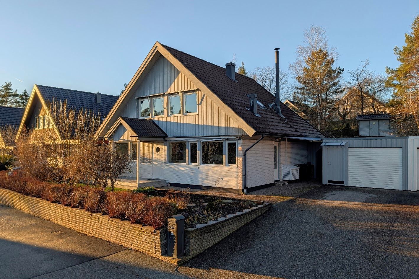 Fasadbild från entrésidan, med dubbla billuppställningsplatser och garage