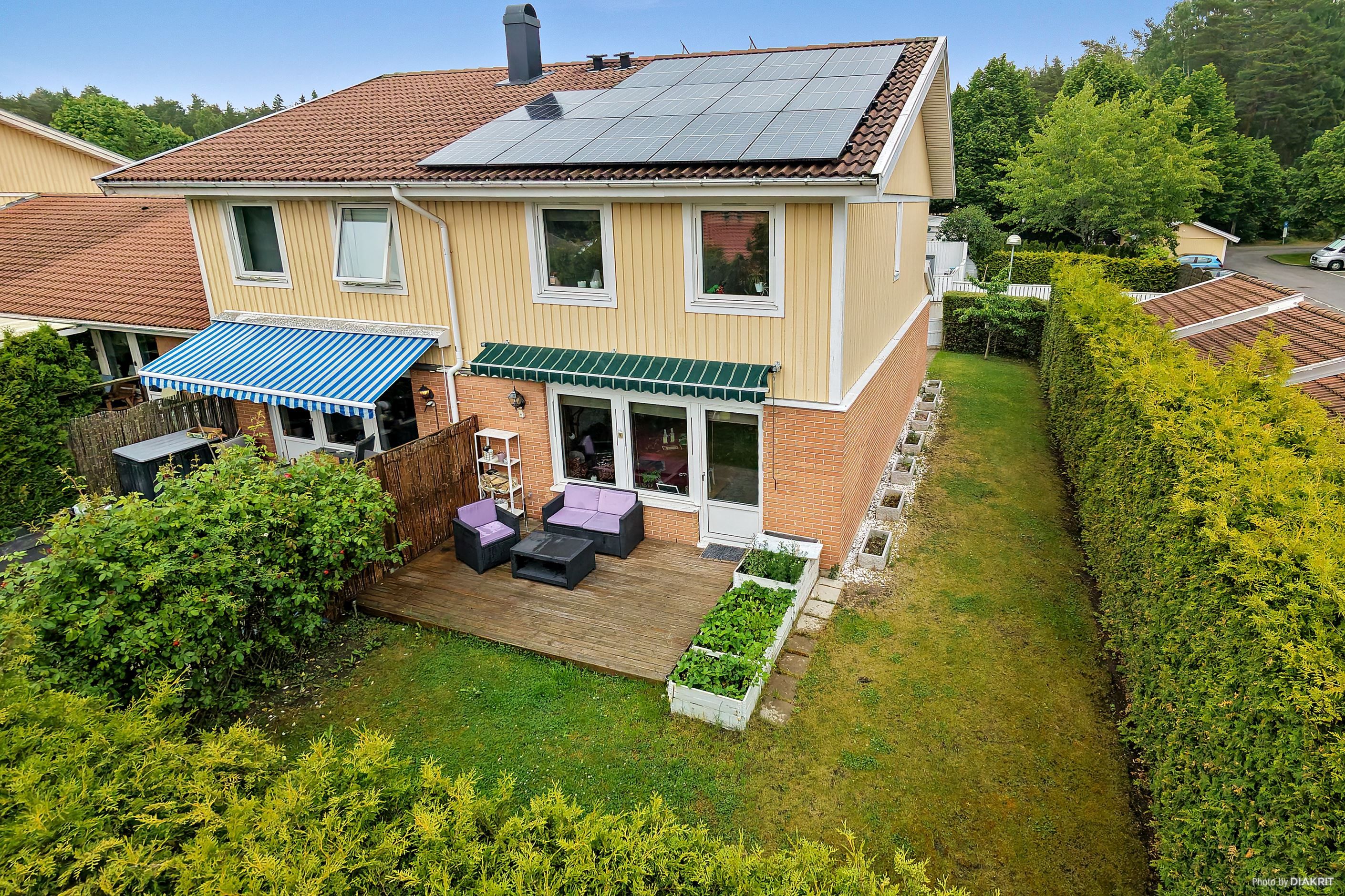 Fasadbild från baksidan av huset, med uteplats och solpaneler
