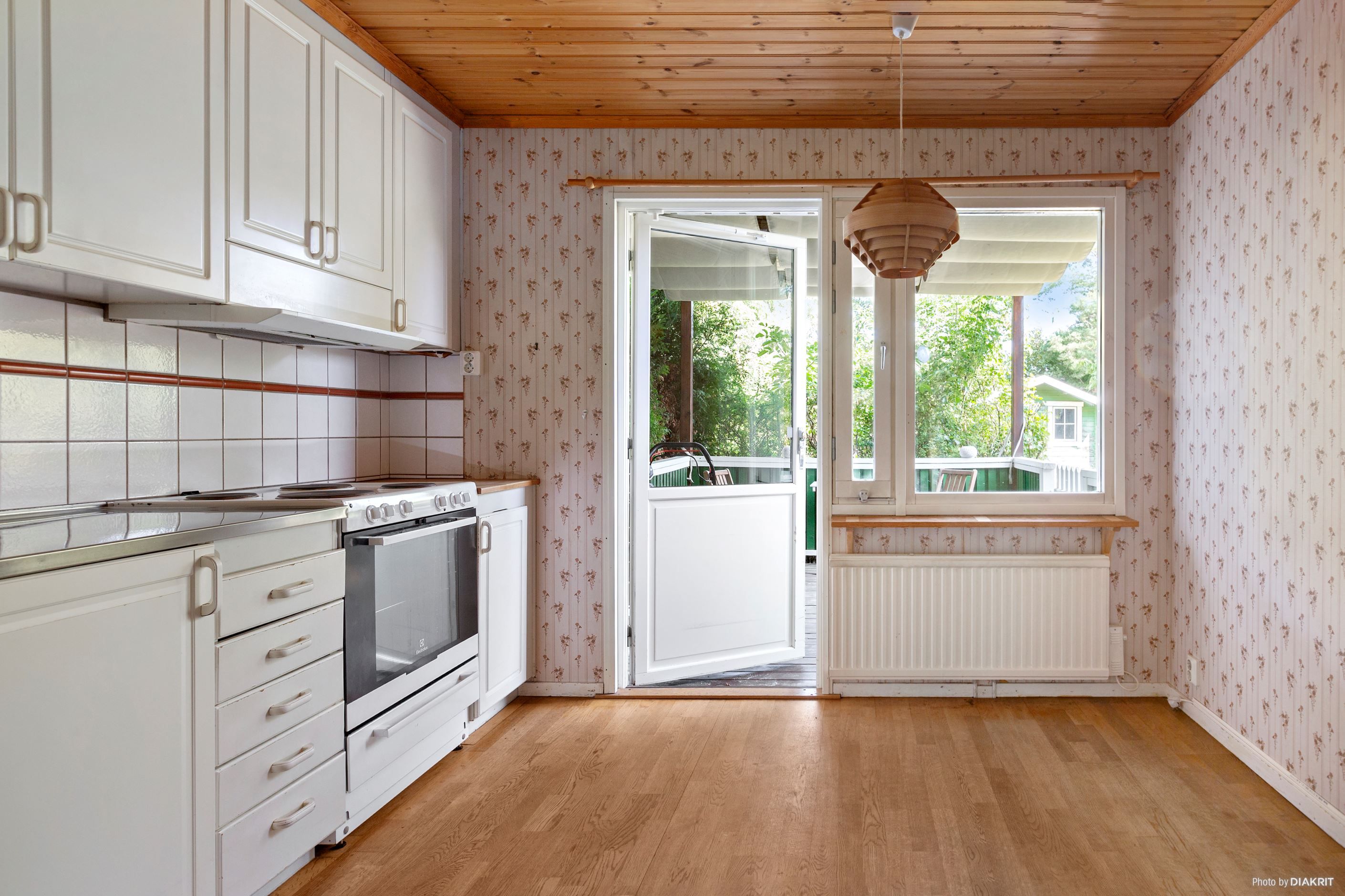 Kök med matplats med utgång till trädäcksförsedd altan/uteplats