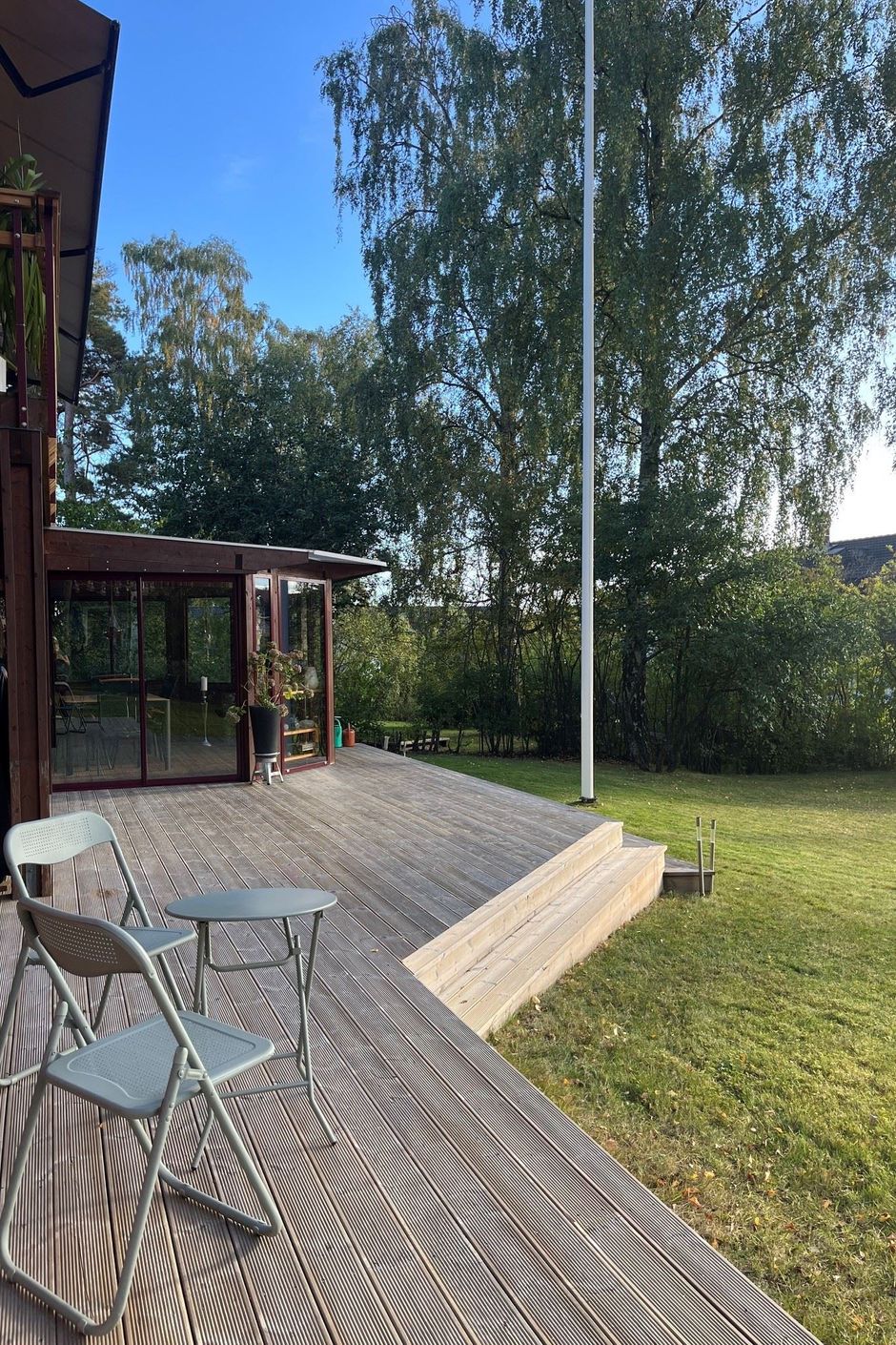 Stor och trädäcksförsedd altan/uteplats och inglasat uterum på baksidan