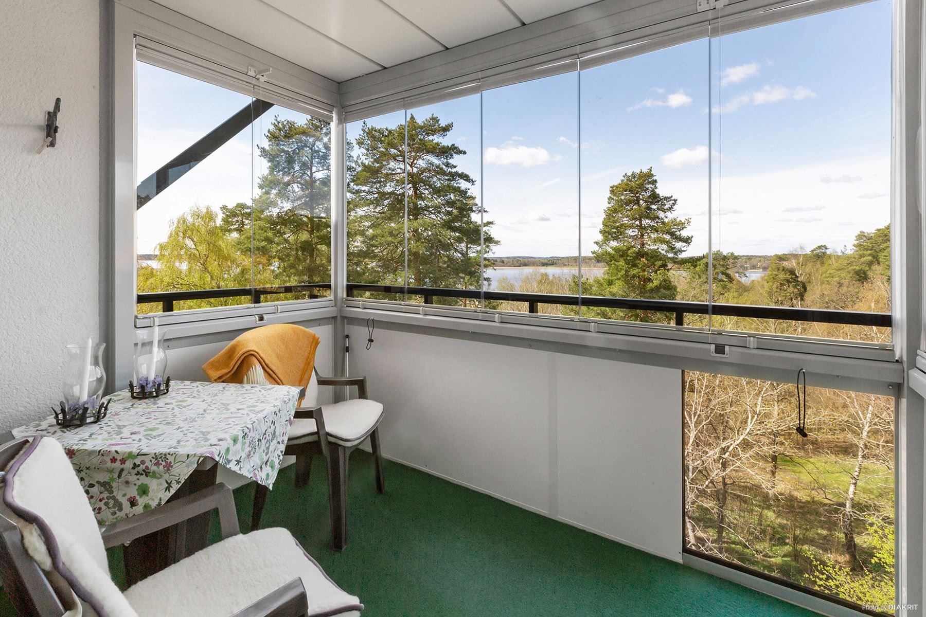 Inglasad balkong med härlig utsikt över grönskande park och mot Mälaren med eftermiddagssol