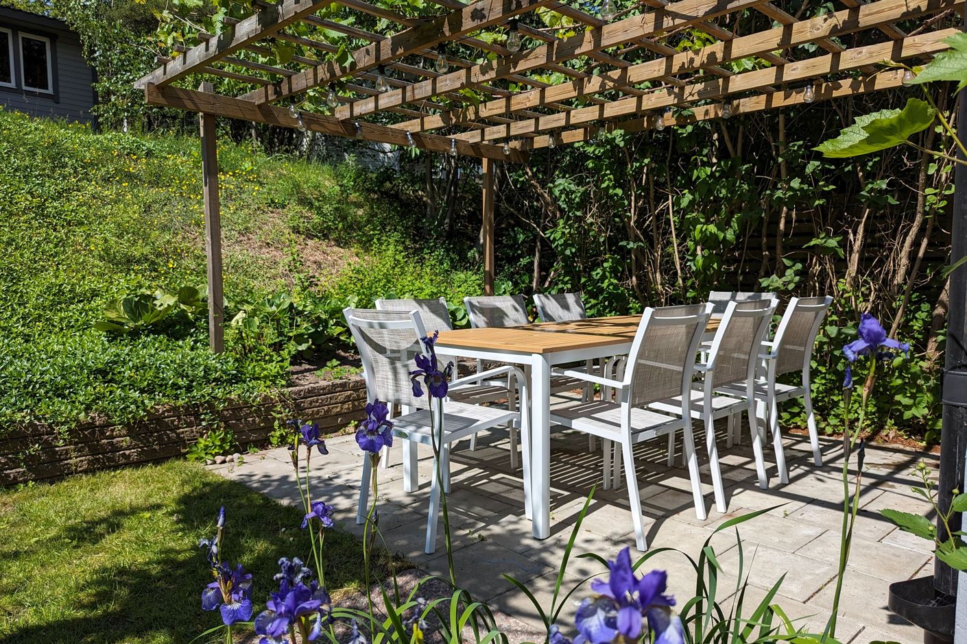 Stenbelagd uteplats på baksidan av huset, med en pergola