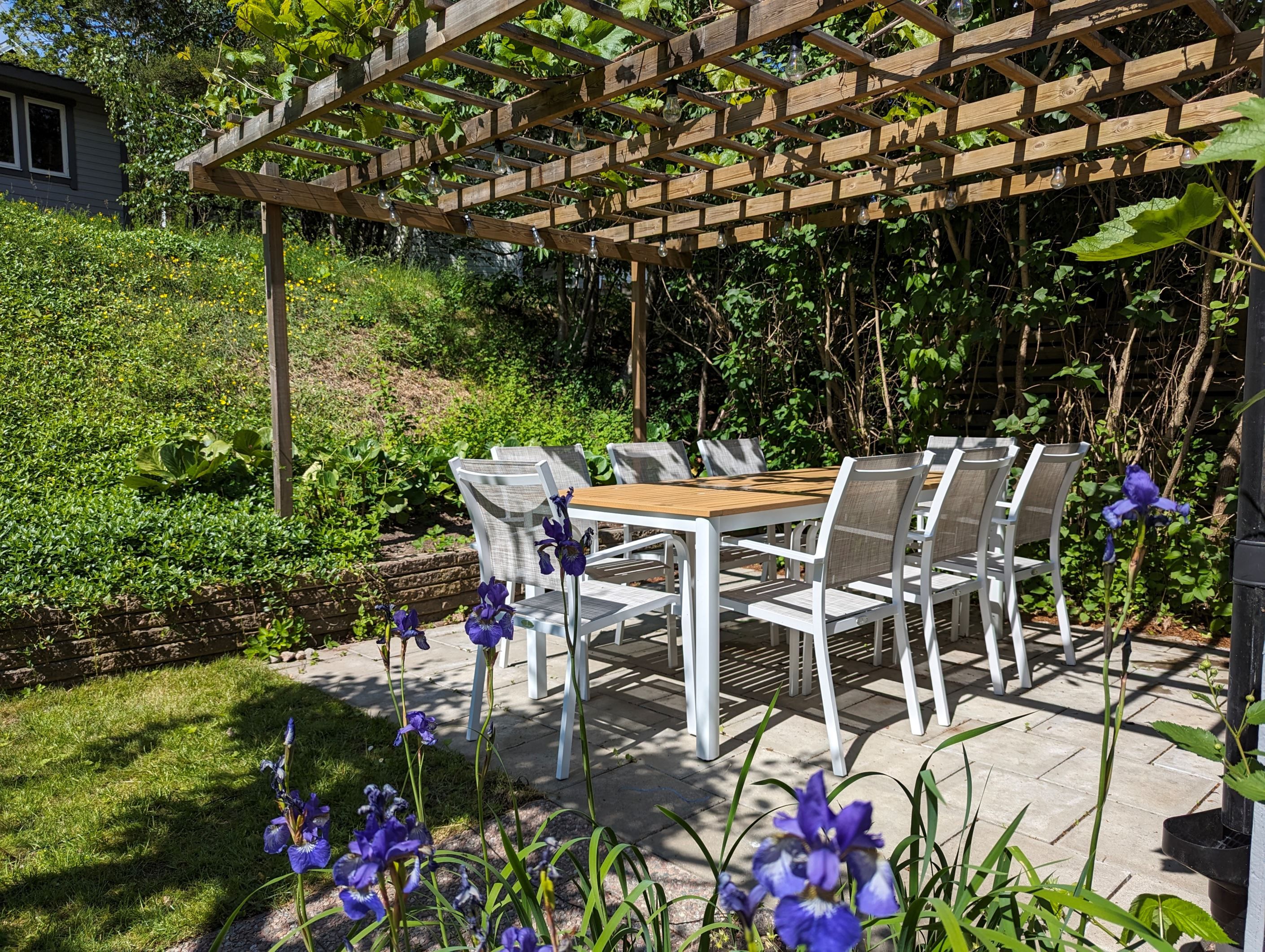 Stenbelagd uteplats på baksidan av huset, med en pergola