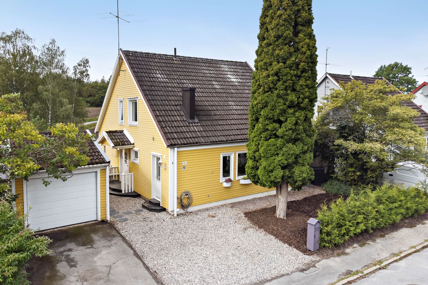 Fasadbild från entrésidan, med garage och biluppställningsplats för 2 bilar